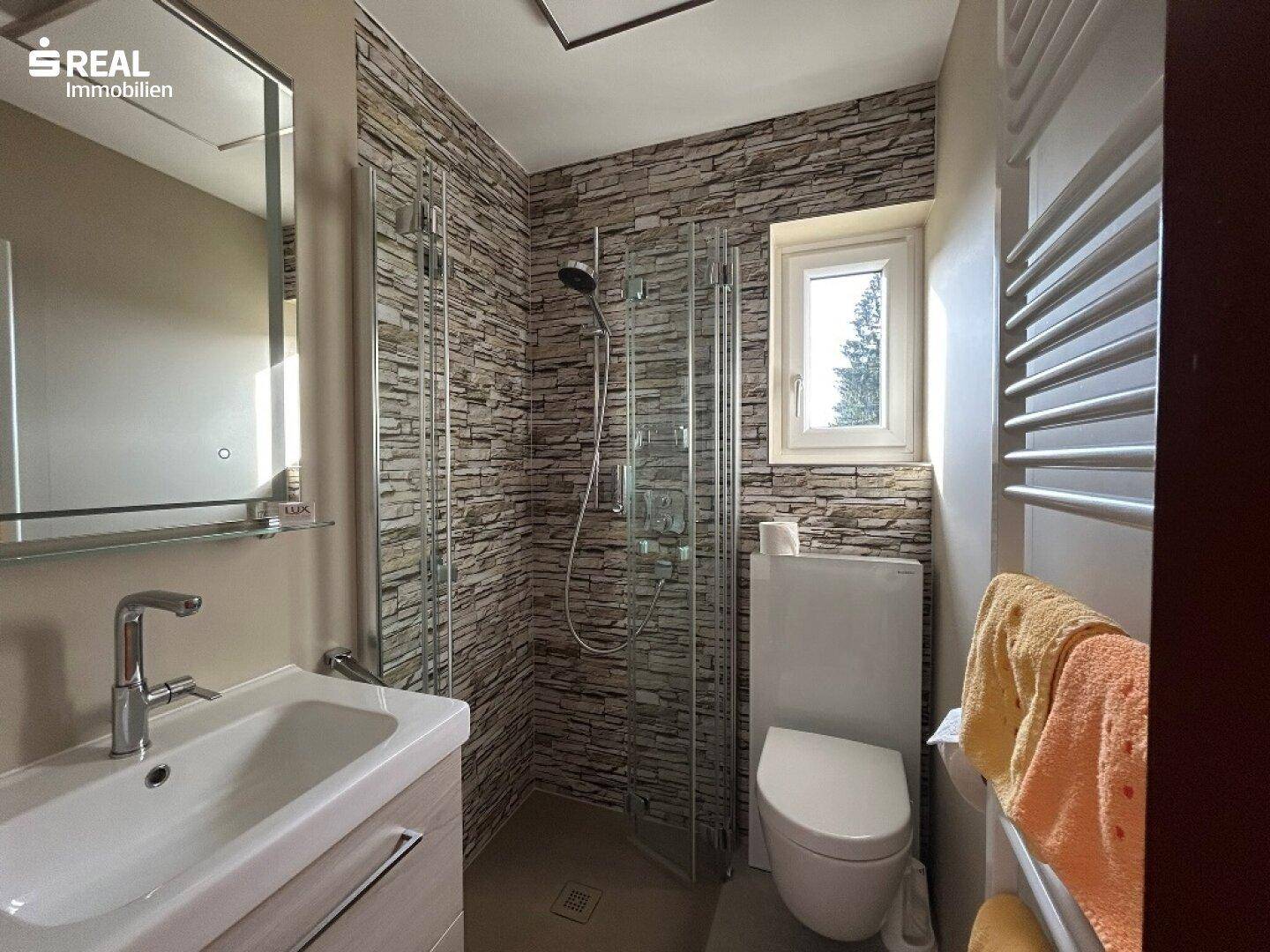 Modernes Badezimmer mit ebenerdiger Dusche, Wand-WC und beheiztem Handtuchhalter.