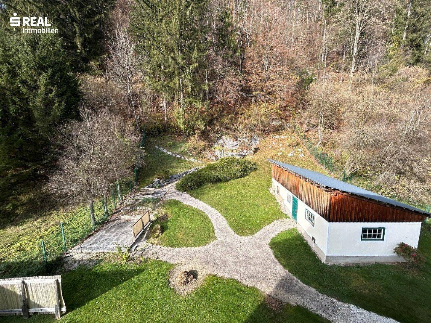 Weitläufiger Gartenbereich mit Wegen, Bäumen und einem kleinen Nebengebäude.