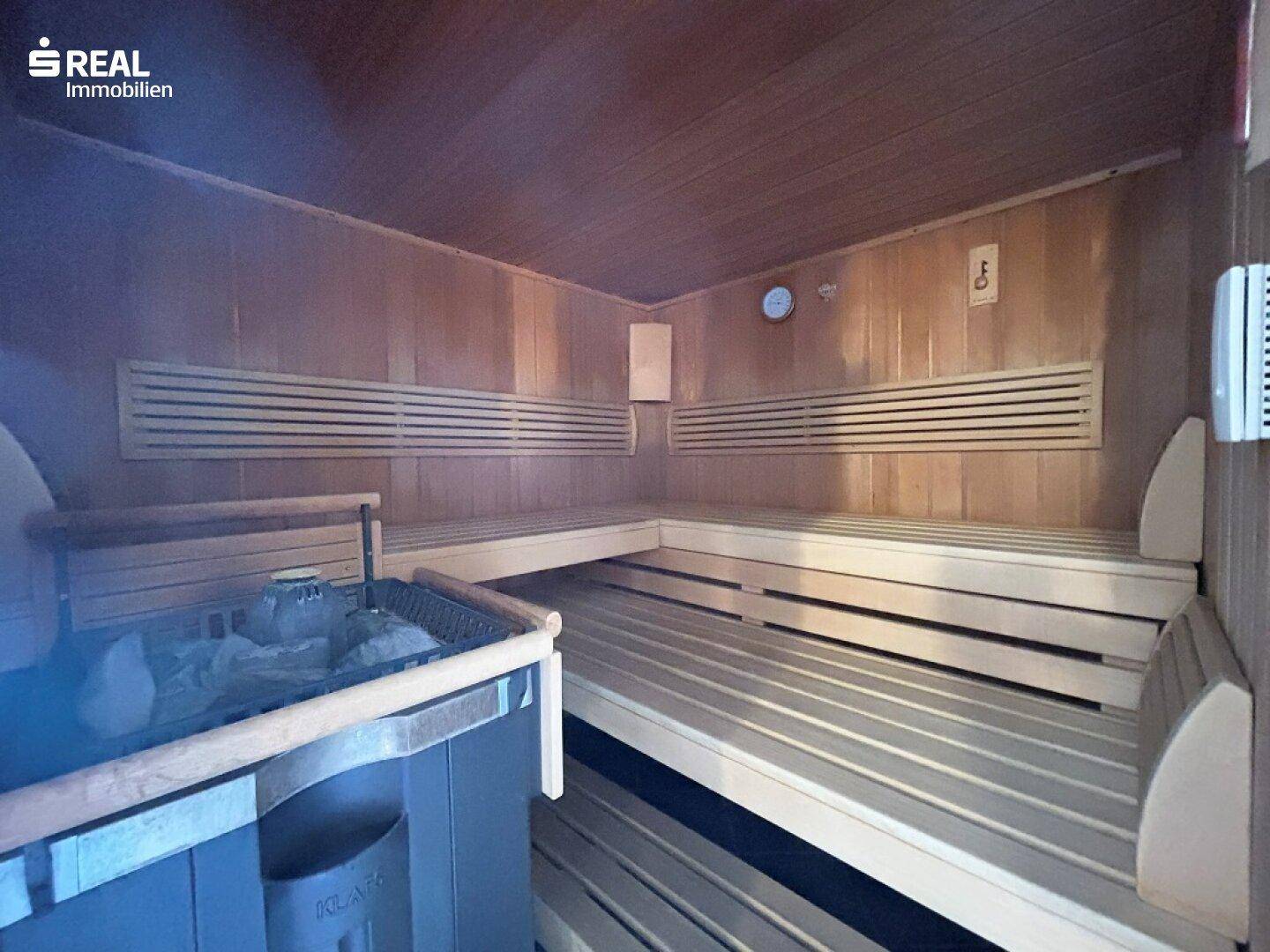 Holzverkleidete Sauna mit Bänken und Ofen, ideal zur Entspannung und Erholung im Wellnessbereich.