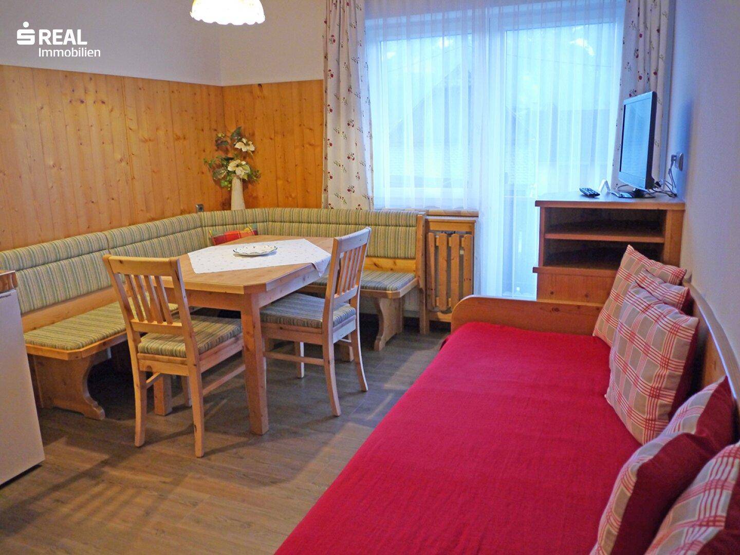 Kombinierter Wohn- und Essbereich mit Holztäfelung, Essecke und Schlafsofa.