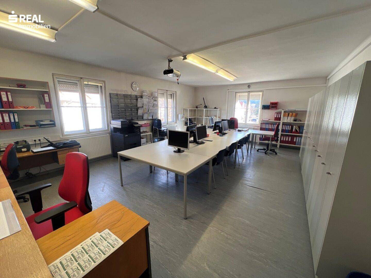 Großes Büro mit mehreren Arbeitsplätzen und Schränken, ideal für ein Team.