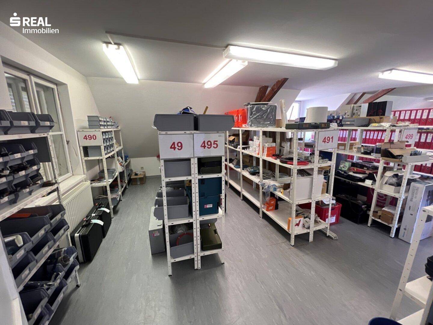 Dachboden als Lagerraum mit Regalsystemen und verschiedenen Materialien, gut organisiert.