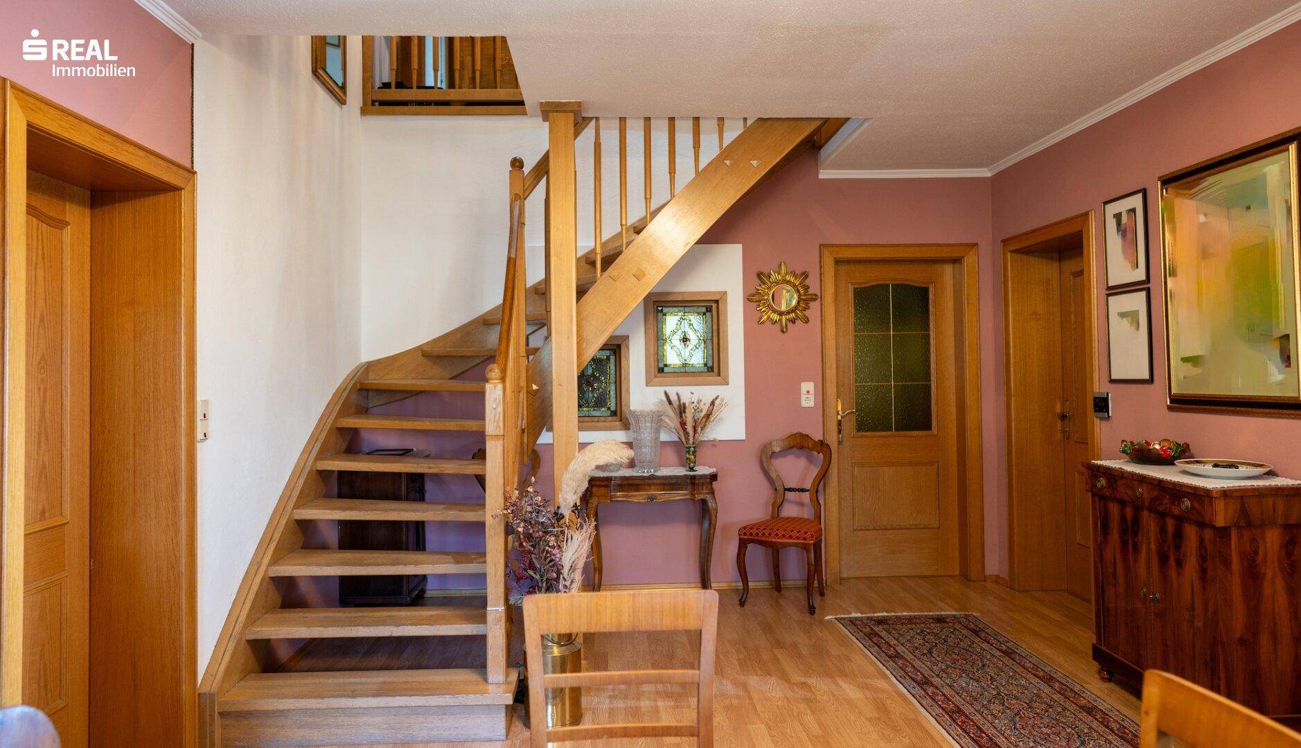 Heller Eingangsbereich mit Holztreppe, Parkettboden und traditioneller Dekoration.