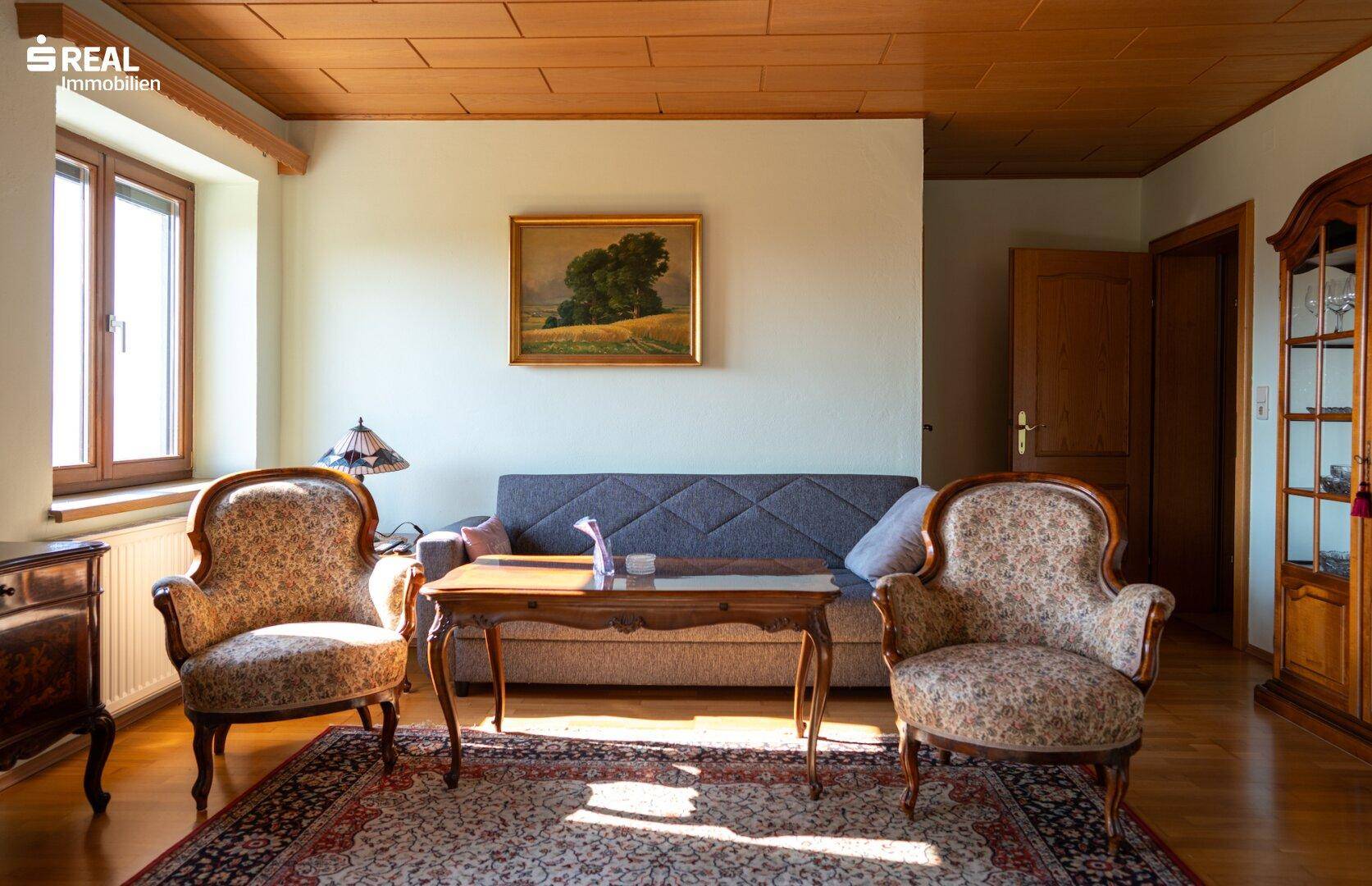 Gemütliches Wohnzimmer mit Holzbalkendecke, Parkettboden und traditionellen Möbeln.