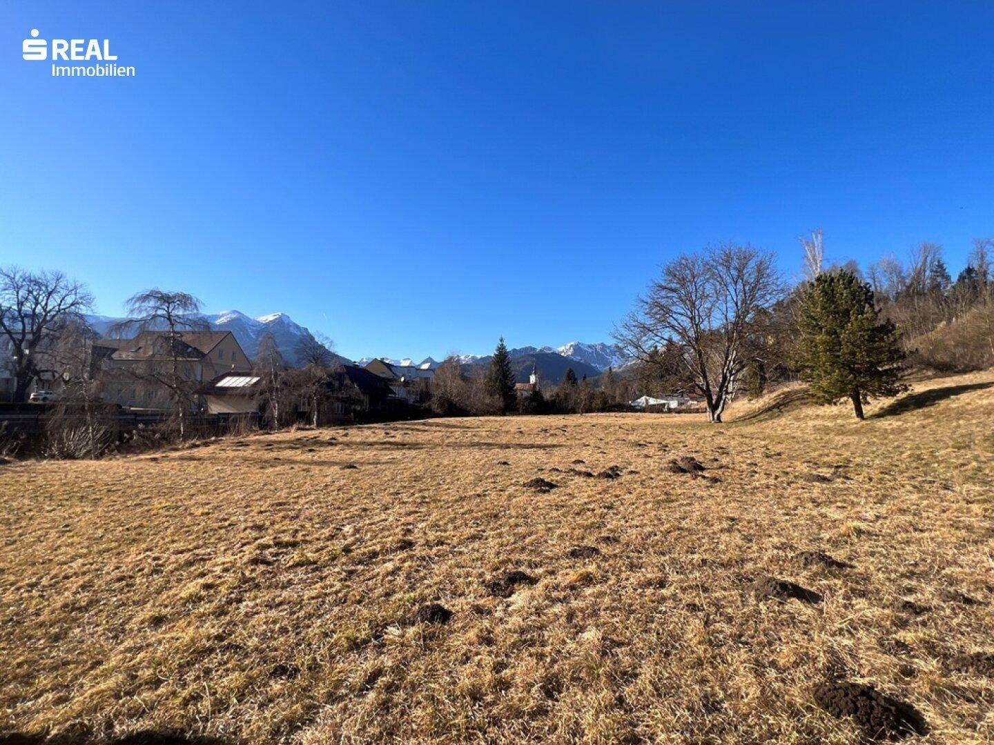 Weitläufiges Grundstück mit Blick auf die umliegende Berglandschaft unter blauem Himmel.