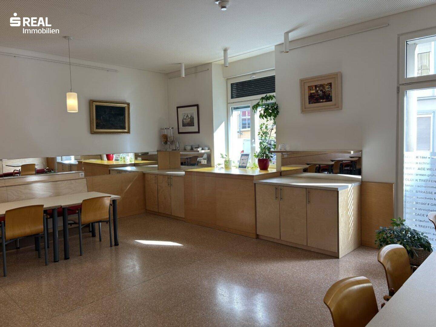 Speisesaal mit Buffetbereich und großen Fenstern, die viel Tageslicht hereinlassen.