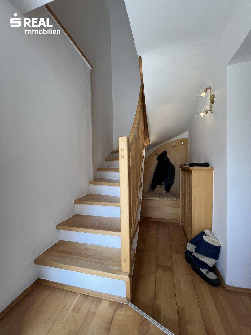 Holztreppe führt in den oberen Bereich, mit Garderobe und Holzboden im Eingangsbereich.