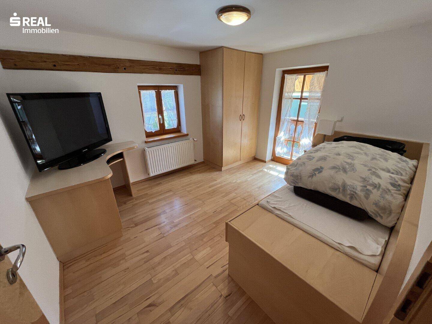 Schlafzimmer mit Einzelbett, Holzmöbeln und Fernseher, ideal als Gäste- oder Kinderzimmer.