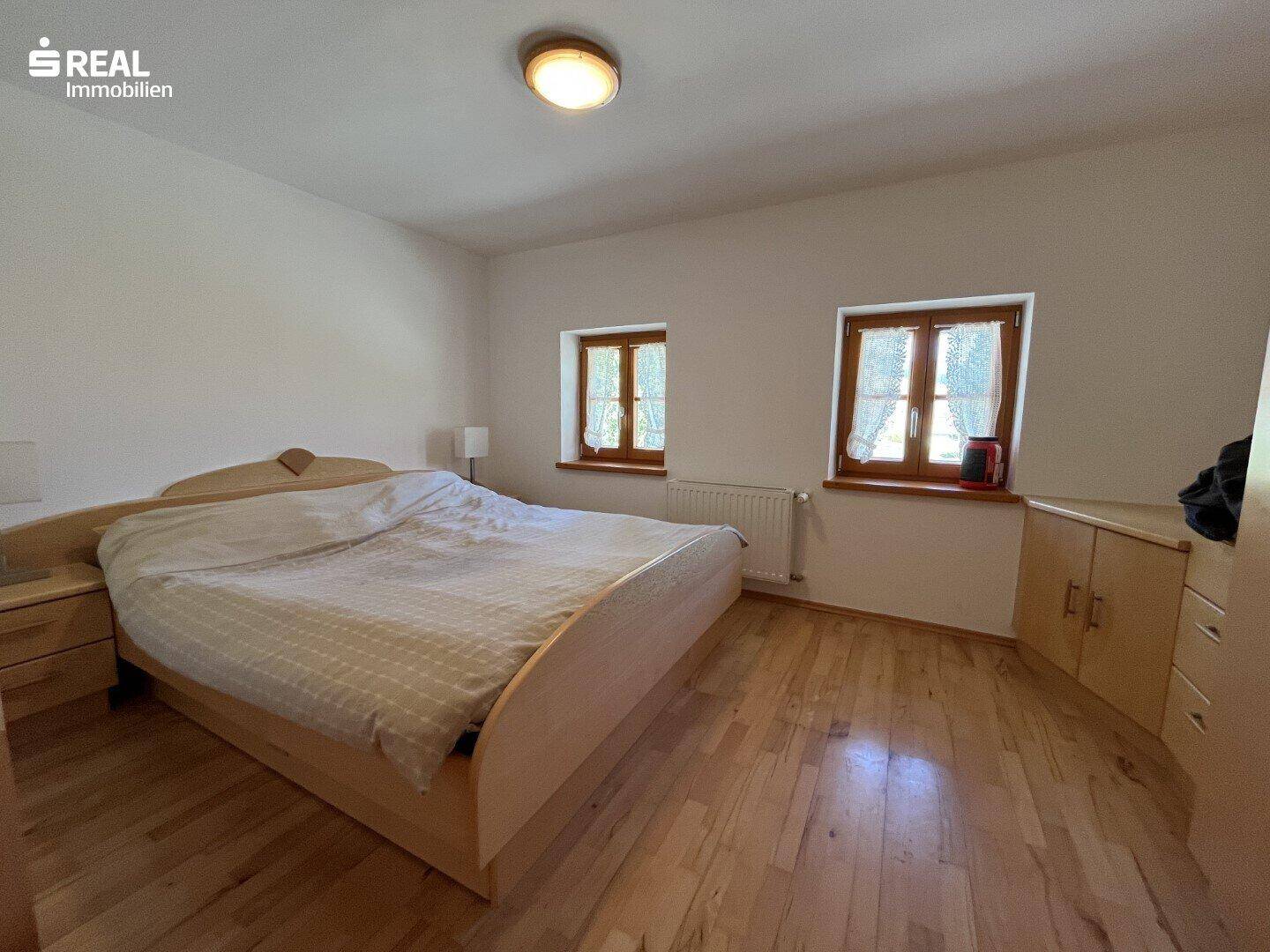 Geräumiges Schlafzimmer mit Doppelbett, Nachttischen und Holzboden in hellem Ambiente.