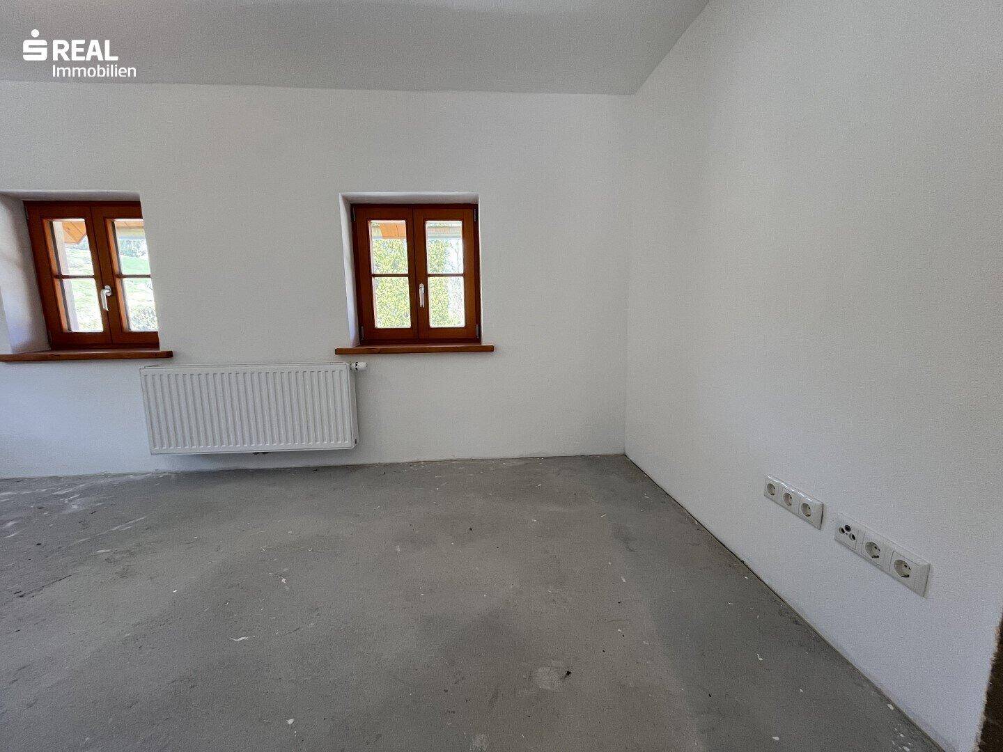 Leerer Raum mit Betonboden und Heizkörper, bereit für die individuelle Gestaltung.