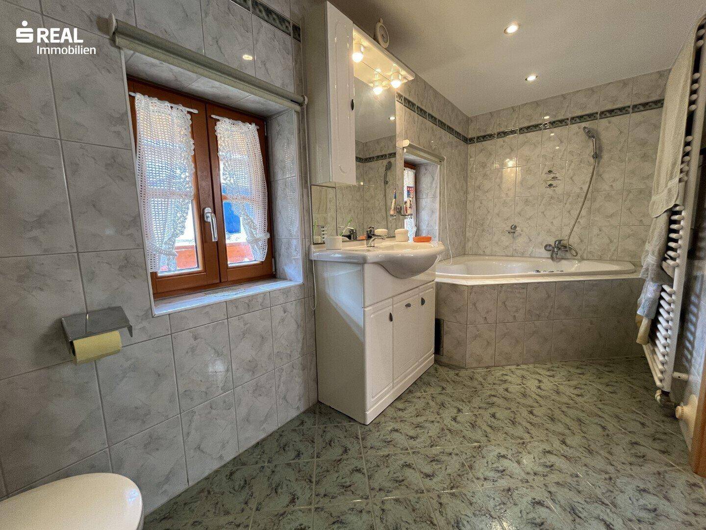Badezimmer mit Badewanne, Waschbecken und Fliesen in traditionellem Design.