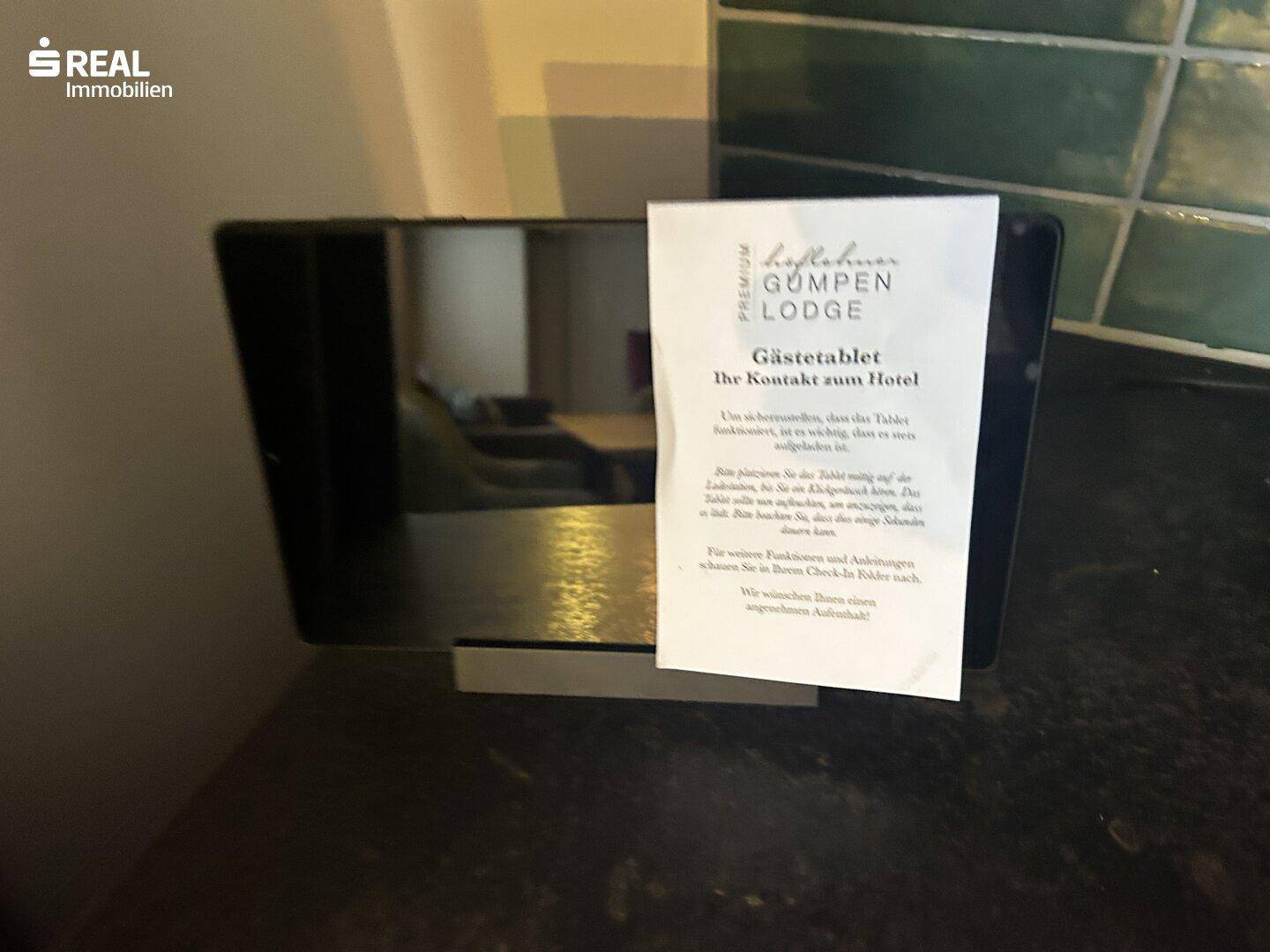 Nahaufnahme eines Gästetablets mit Informationen zum Hotel, platziert auf einer dunklen Oberfläche.