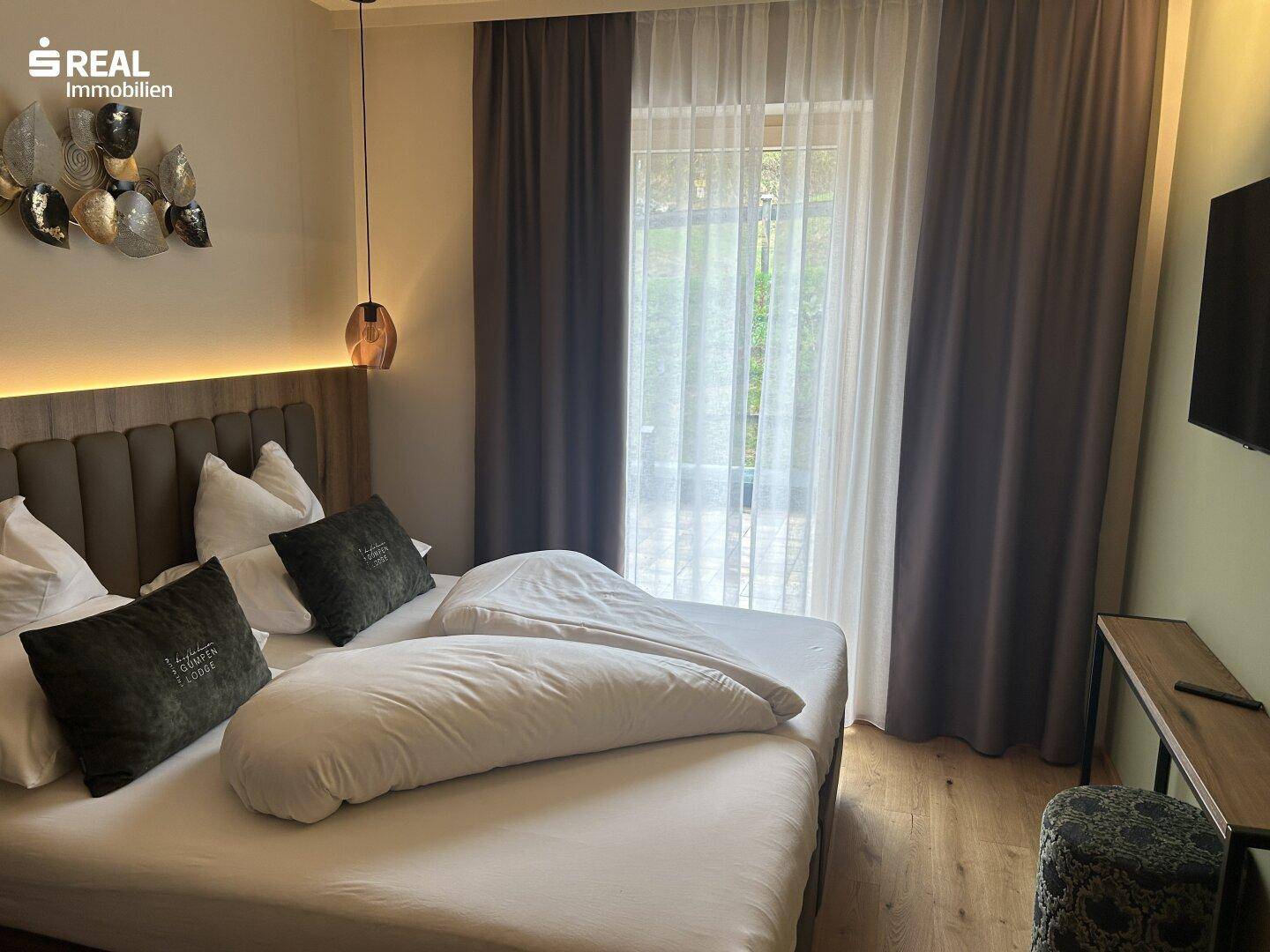 Helles Schlafzimmer mit Zugang zu einem Balkon oder einer Terrasse und einem Flachbildfernseher.