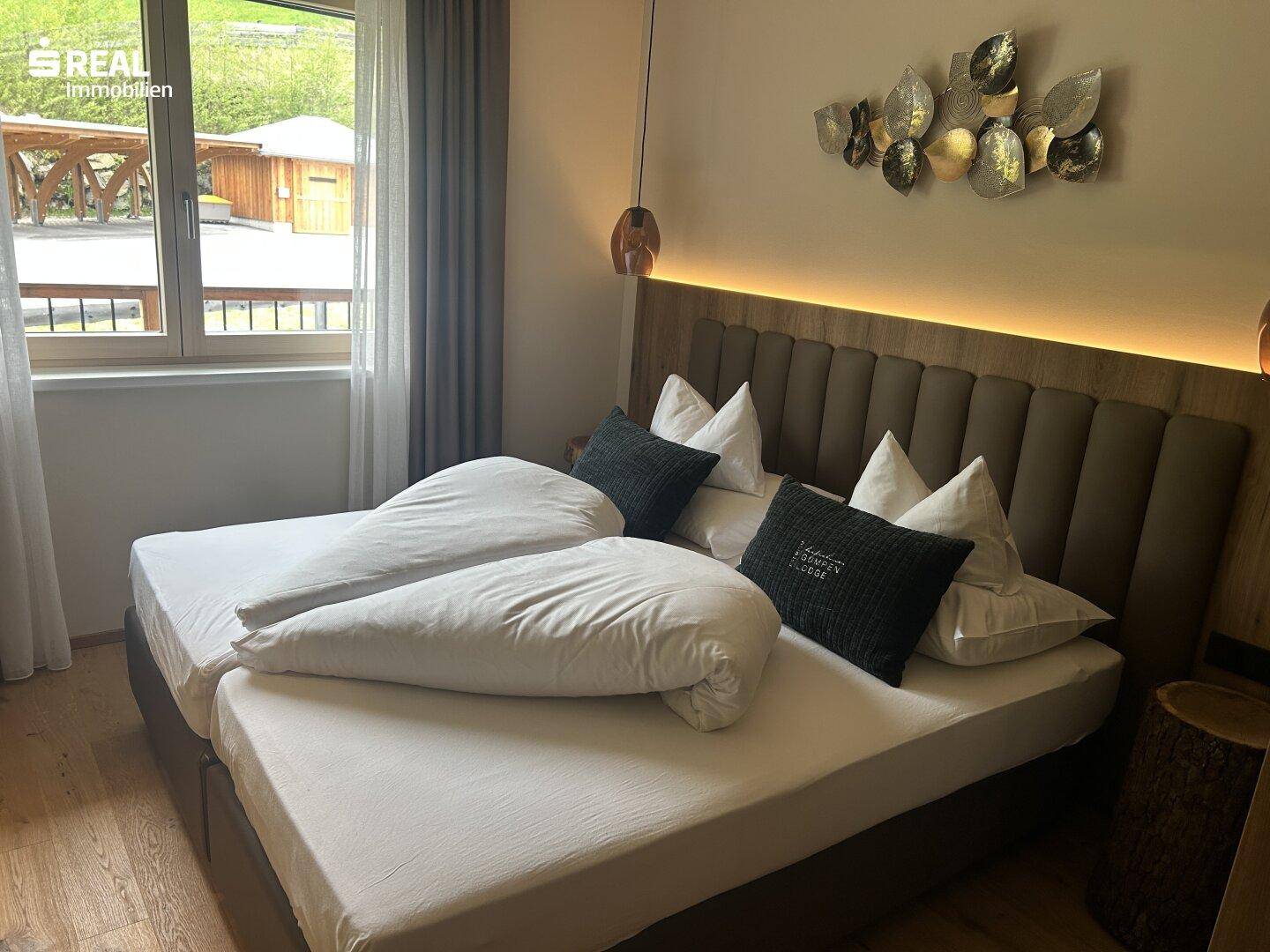 Gemütliches Schlafzimmer mit Doppelbett, Holzkopfteil und Blick ins Grüne.