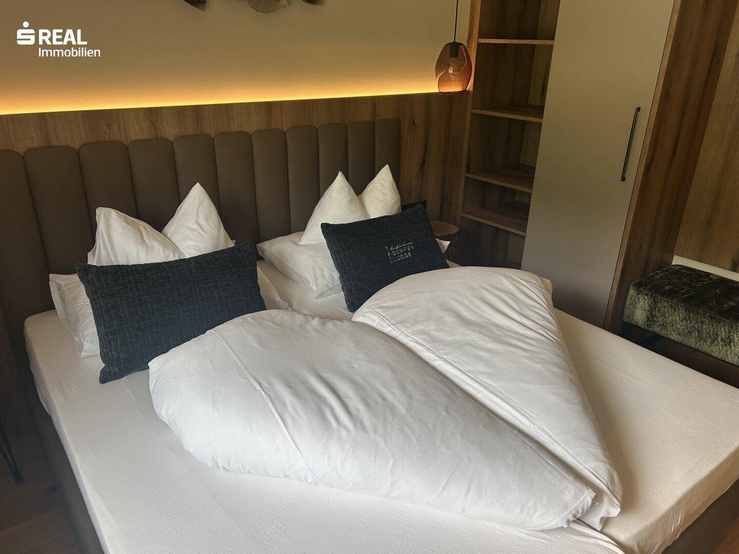 Modernes Schlafzimmer mit bequemen Betten, Holzelementen und indirekter Beleuchtung.
