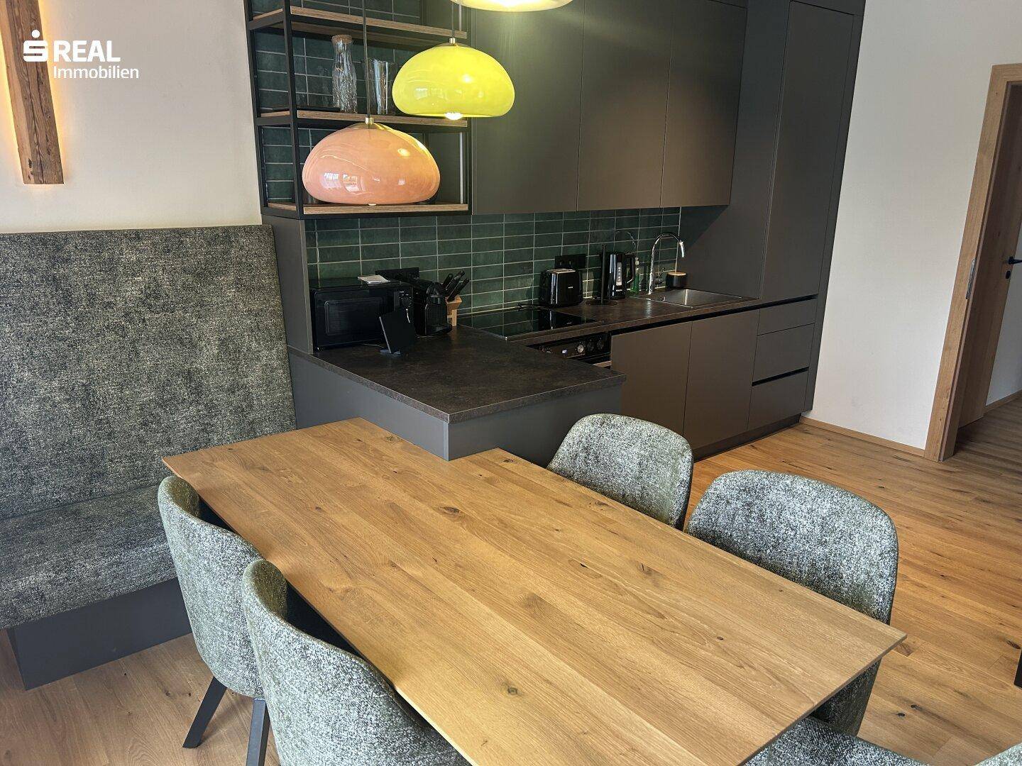 Moderne Küche mit dunklen Schränken, Holztisch und integrierter Sitzbank.