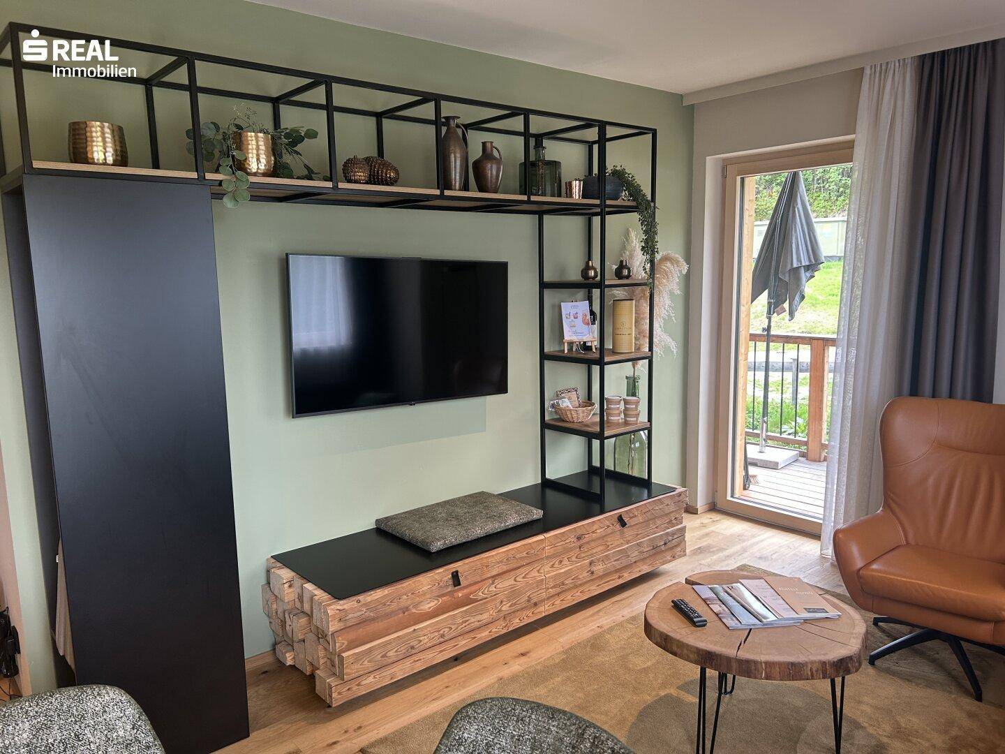 Gemütliches Wohnzimmer mit Holzboden, modernem TV-Möbel und Zugang zum Außenbereich.