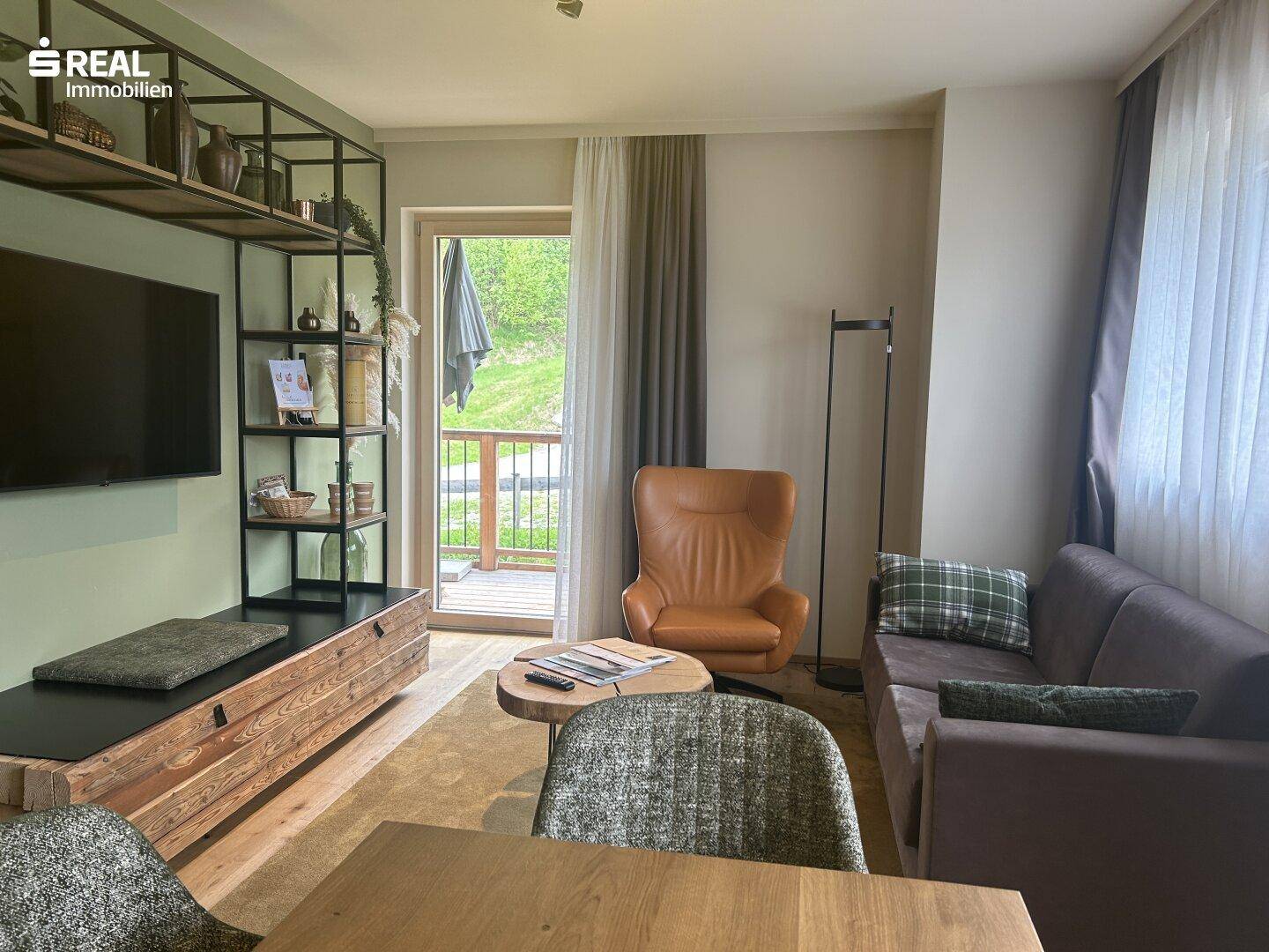 Helles Wohnzimmer mit bequemen Möbeln, Holzboden und Zugang zu einem Balkon.