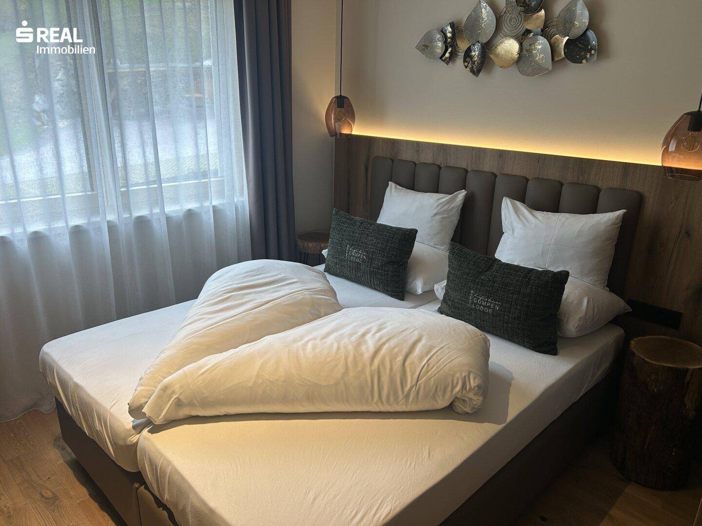 Gemütliches Schlafzimmer mit Doppelbett, Holzkopfteil und stilvoller Wanddekoration.