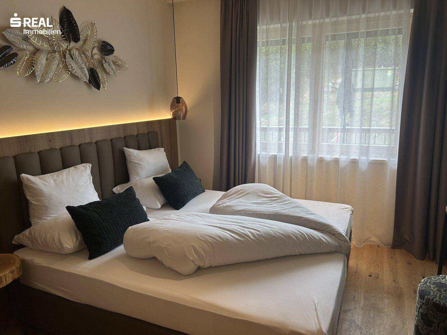 Helles Schlafzimmer mit großem Bett, weichen Kissen und Vorhängen für angenehme Atmosphäre.