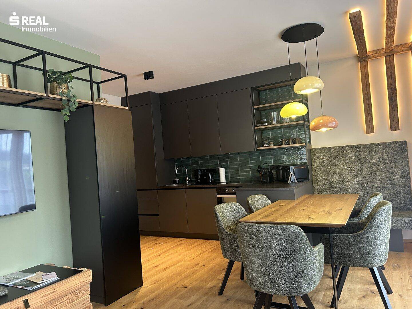 Offene Küche mit dunklen Schränken, Essbereich und integrierter Sitzbank in modernem Design.