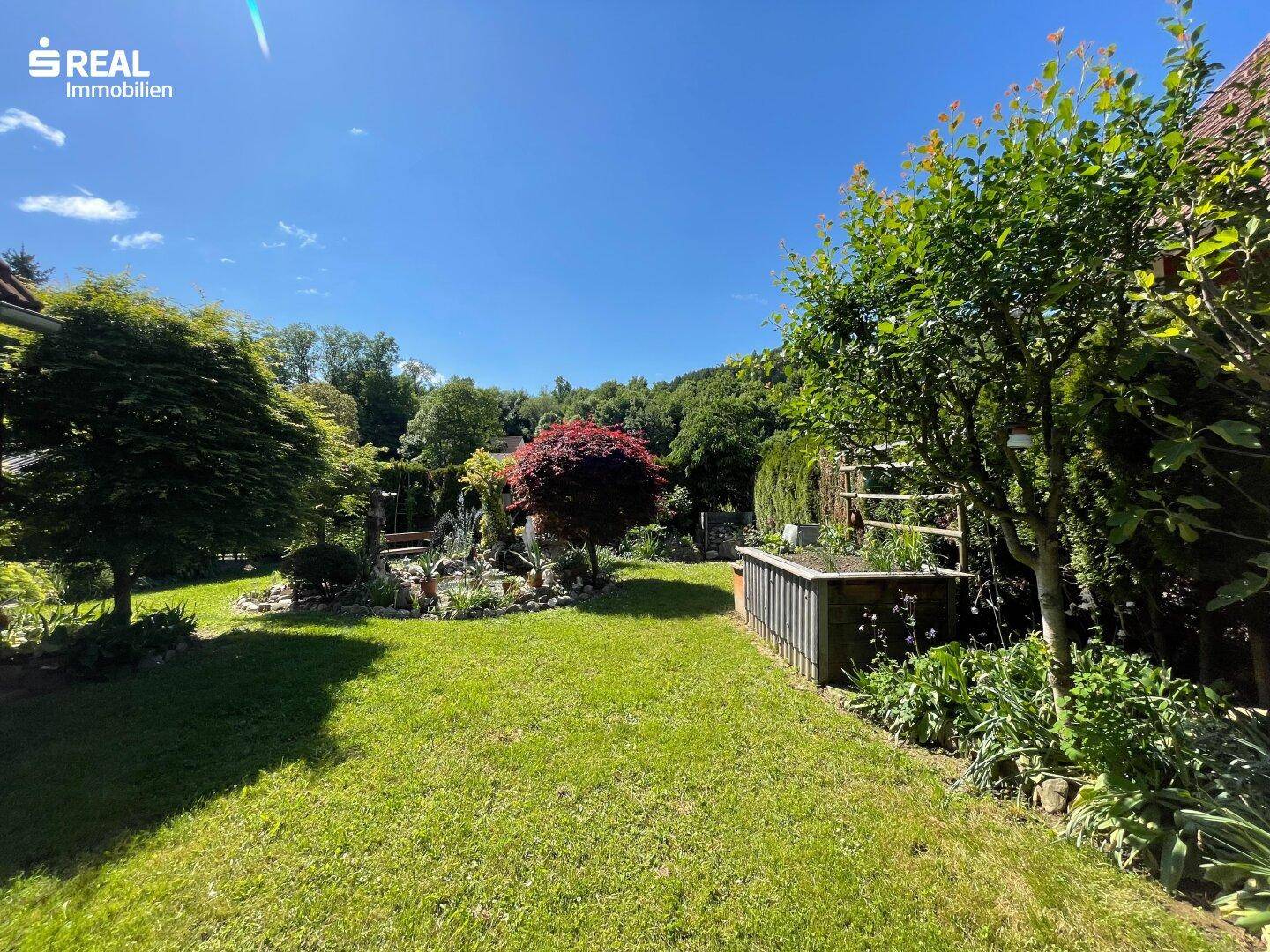 Weitläufiger, gepflegter Garten mit großer Rasenfläche, umgeben von Bäumen und Sträuchern.