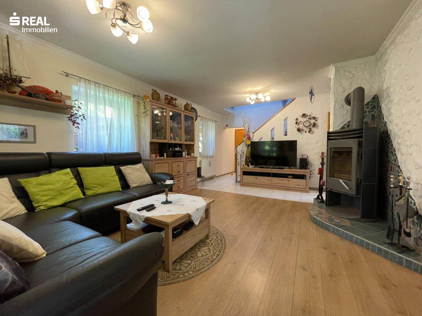 Geräumiges Wohnzimmer mit Ledersofa, Holzboden und einem gemütlichen Holzofen für kalte Tage.