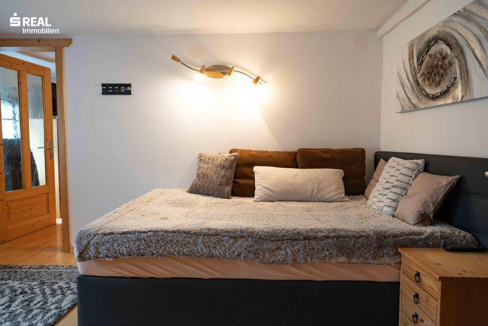 Helles Schlafzimmer mit großem Bett, weichen Kissen und Holztüren im Hintergrund.