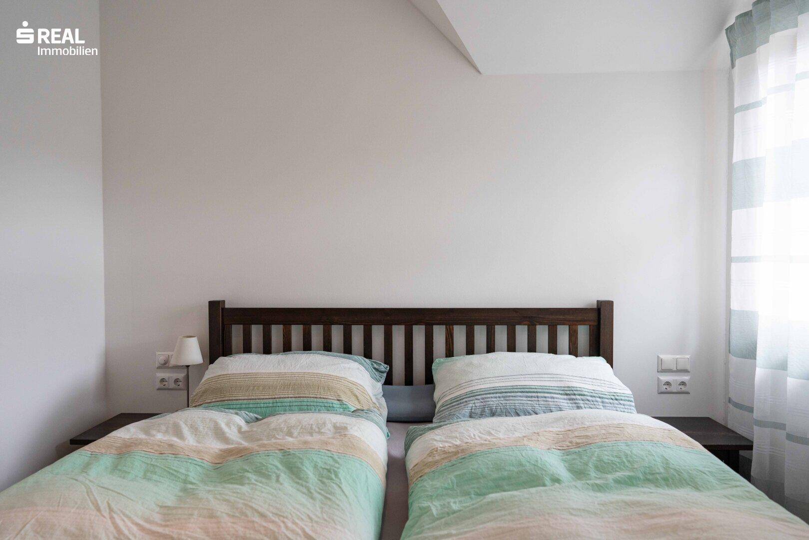 Schlafzimmer mit Doppelbett, Nachttischen und gestreiften Vorhängen, hell und freundlich.