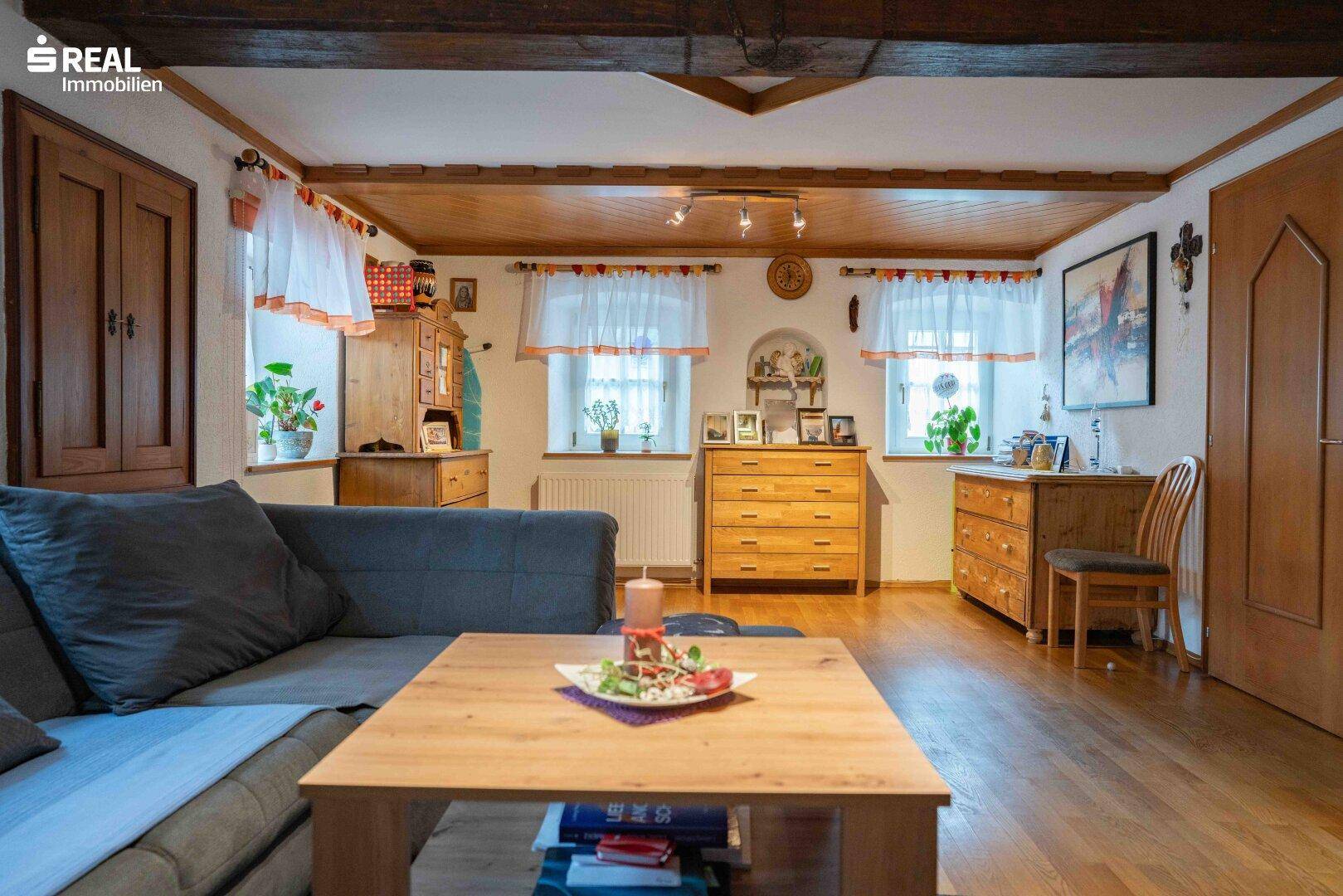 Geräumiges Wohnzimmer mit Holzboden, mehreren Fenstern und traditionellen Holzmöbeln.
