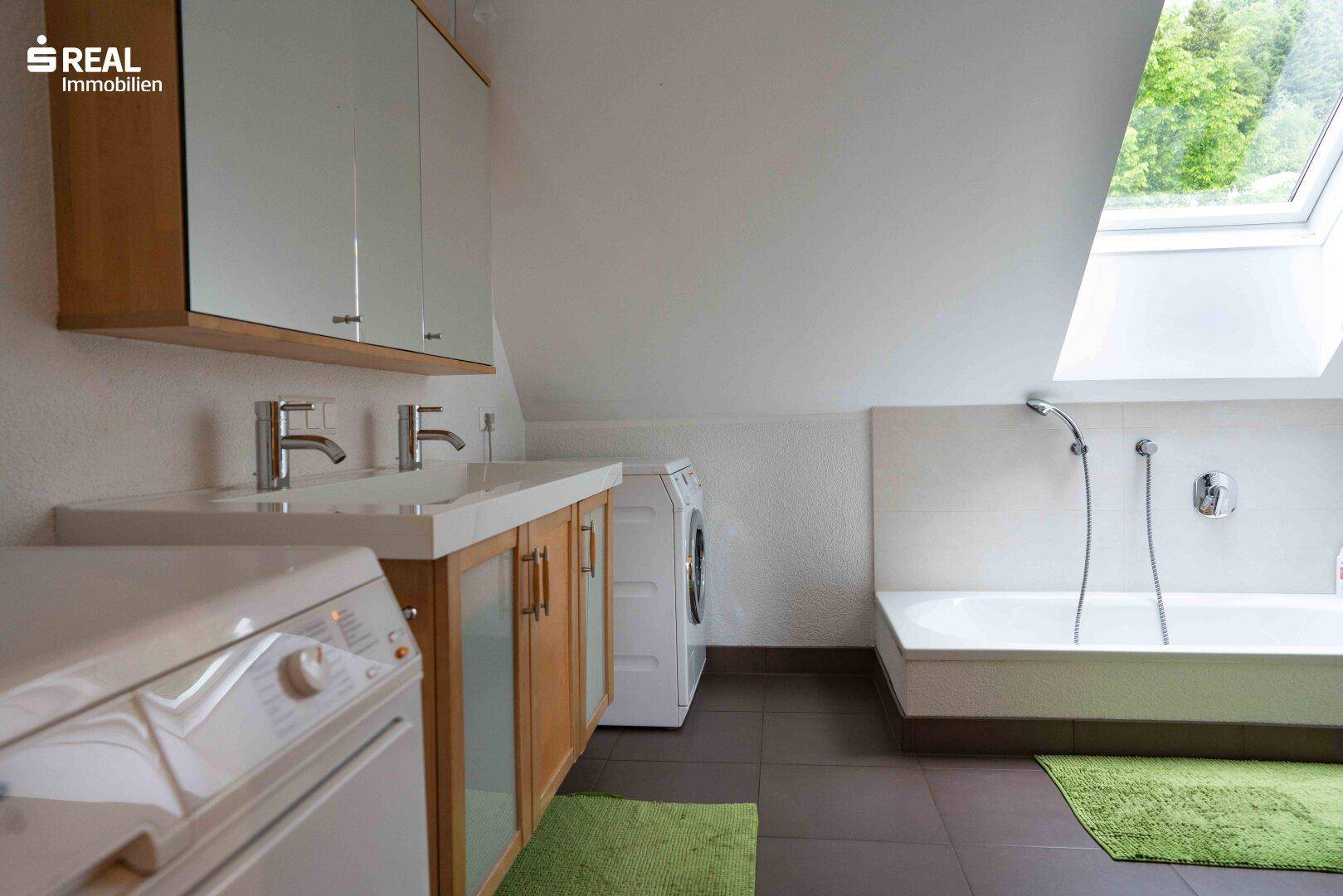 Geräumiges Badezimmer im Dachgeschoss mit Doppelwaschbecken, Badewanne und Dachfenster.