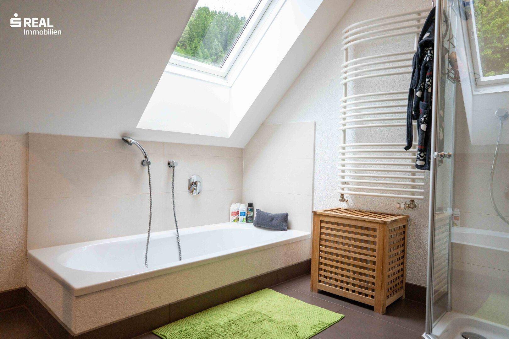 Helles Badezimmer mit Badewanne, Dusche, beheiztem Handtuchhalter und Dachfenster.