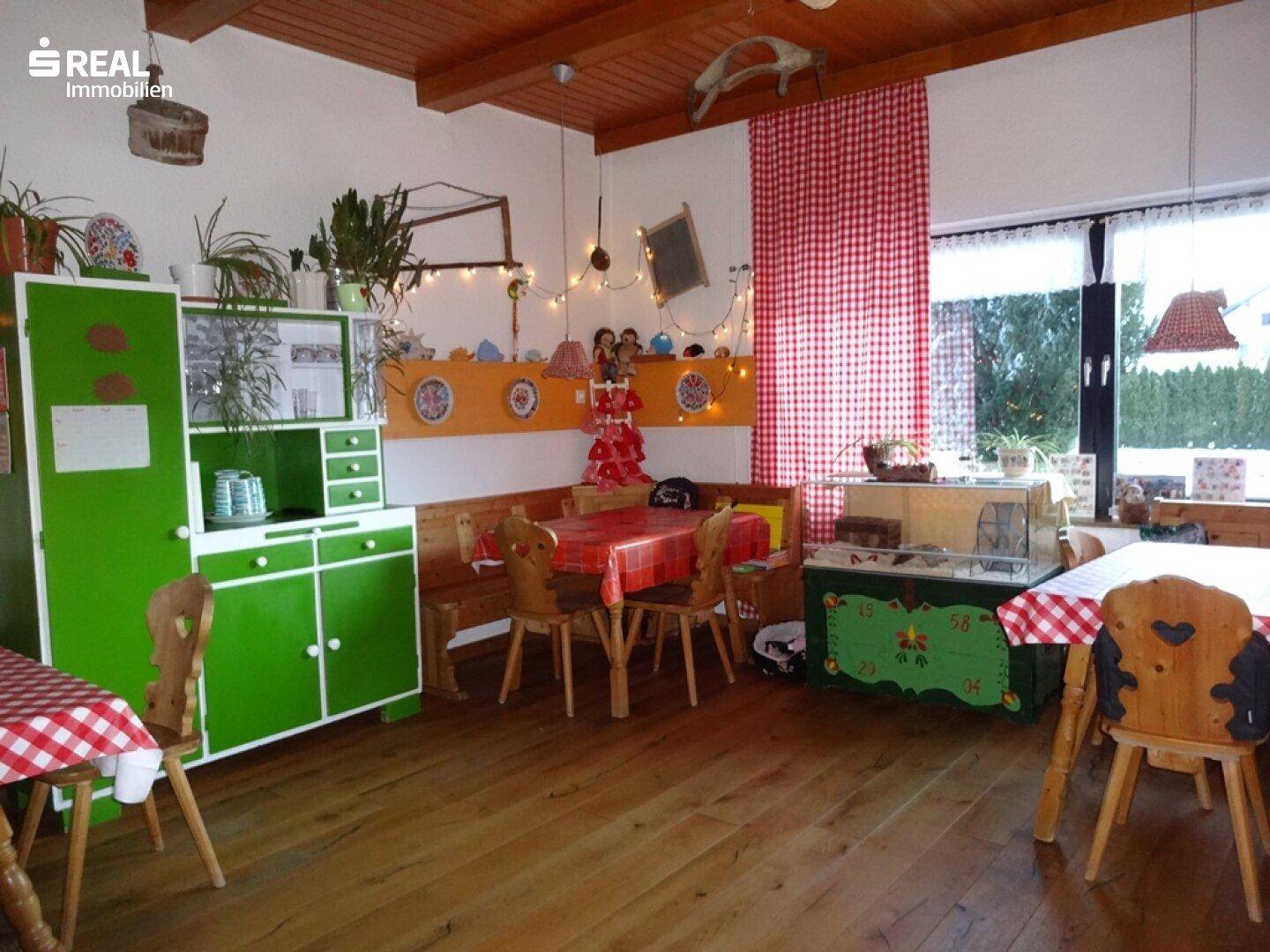 Rustikaler Essbereich mit Holztischen, grünen Schränken und traditioneller Dekoration.