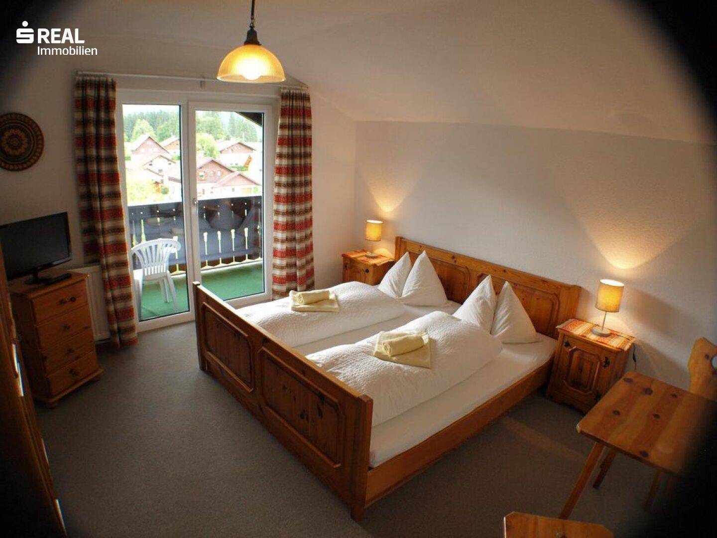 Gemütliches Schlafzimmer mit Doppelbett, grauem Teppich und Balkonzugang.