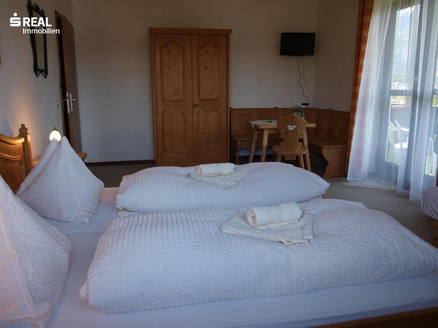 Komfortables Schlafzimmer mit Doppelbett, grauem Teppich und Balkonzugang.