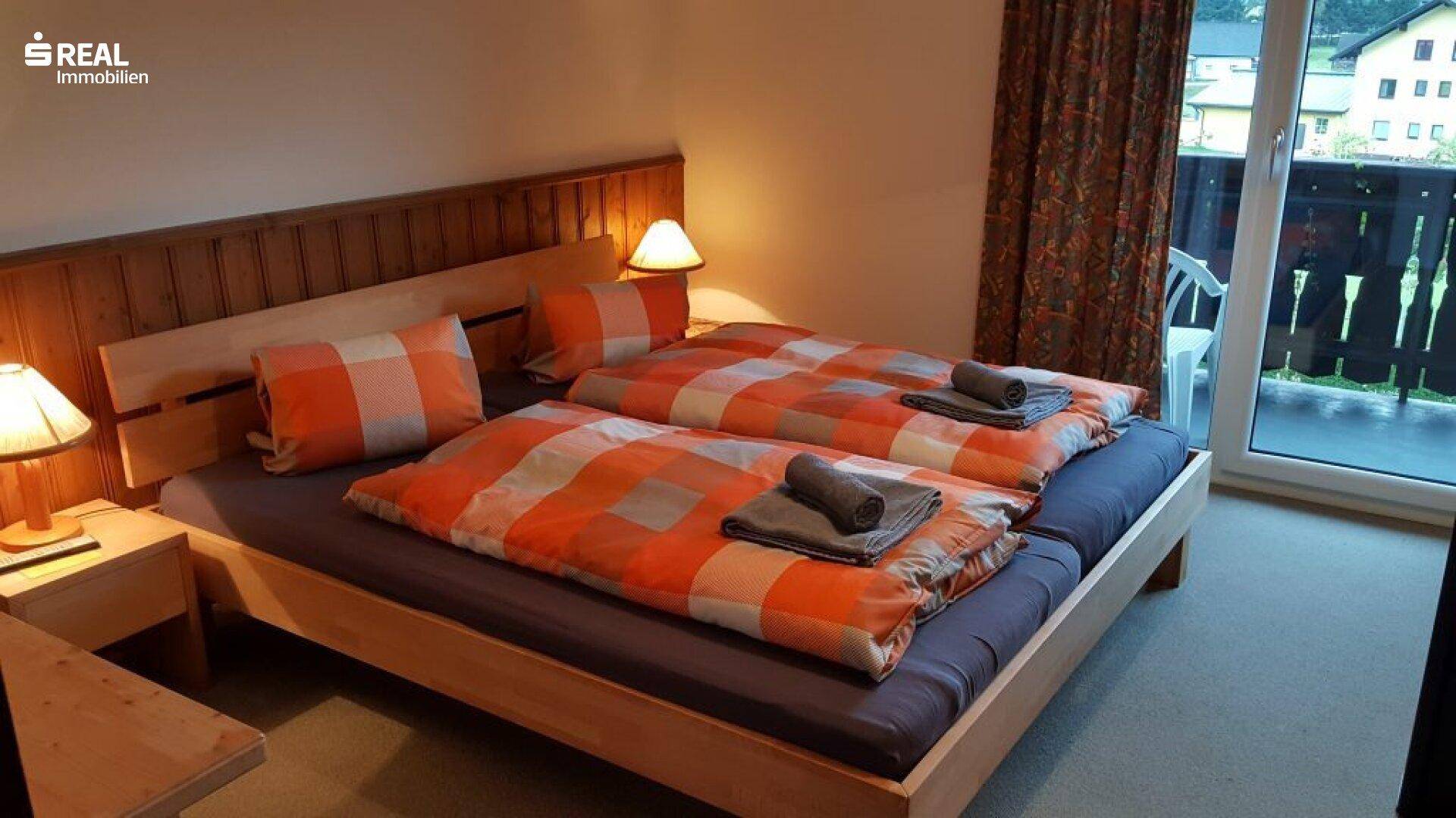 Schlafzimmer mit Doppelbett, Holzvertäfelung und Zugang zu einem Balkon.