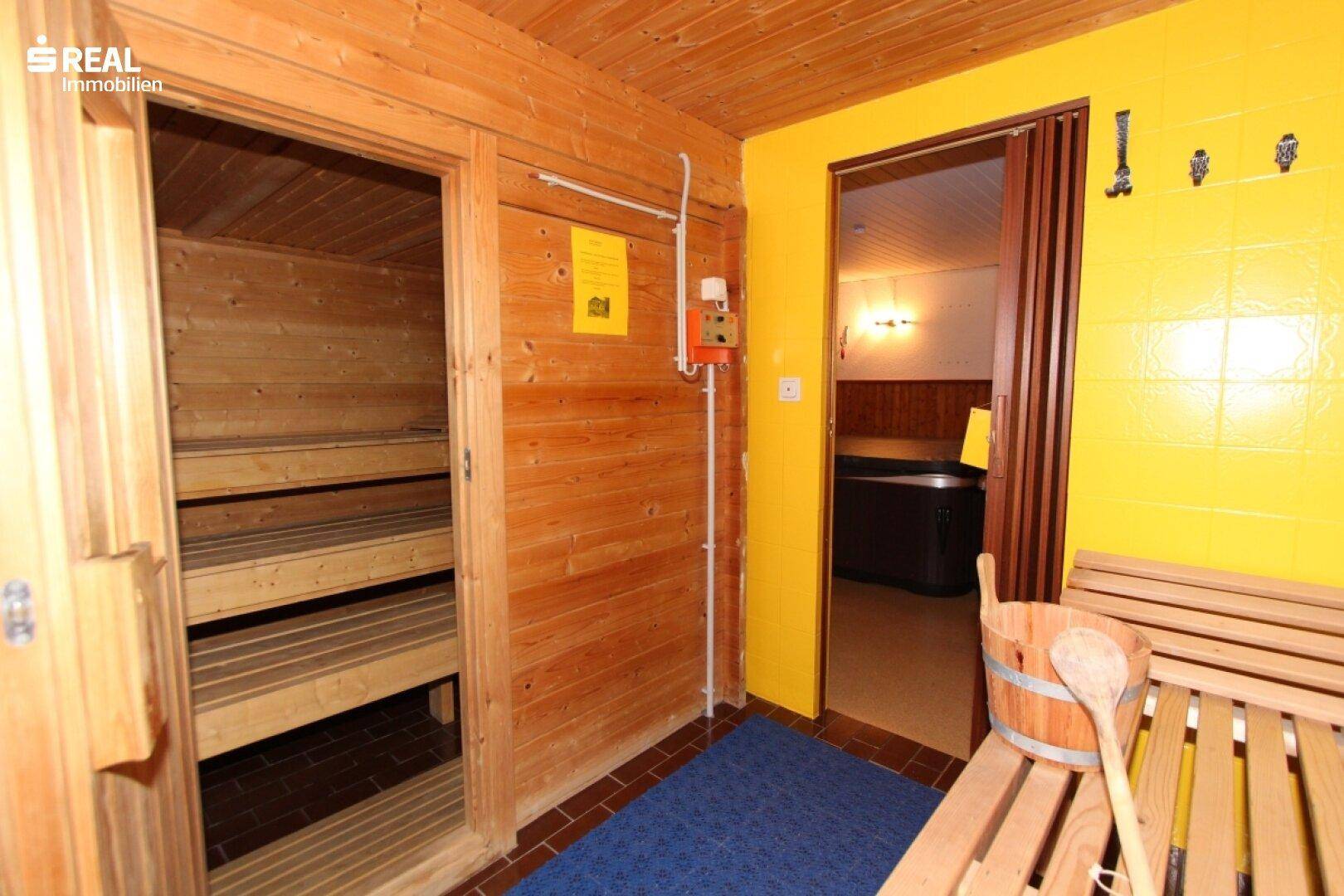 Sauna mit Holzbänken und Blick auf den angrenzenden Whirlpoolbereich.