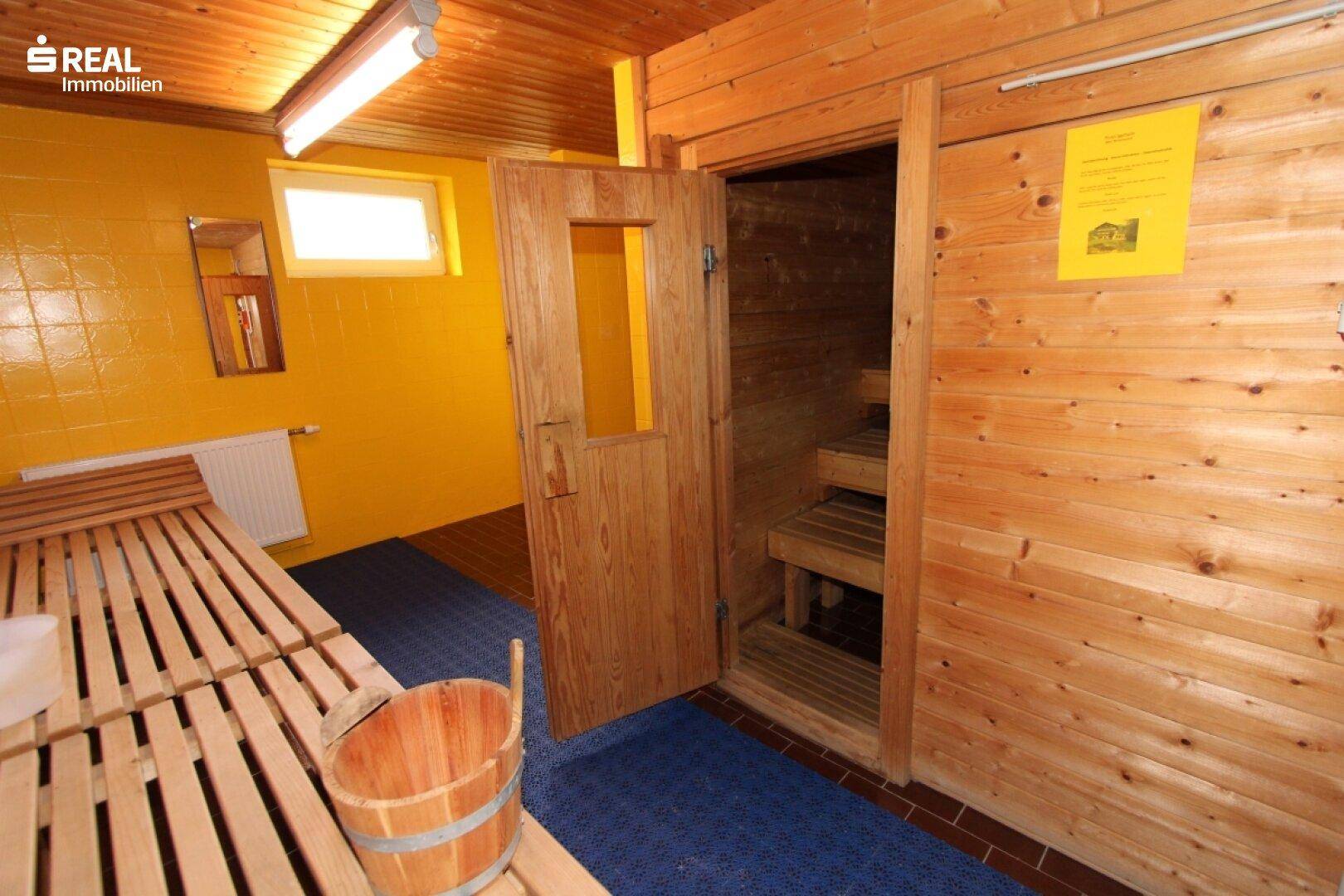 Innenansicht der Sauna mit Holzbänken und kleinem Fenster für natürliches Licht.