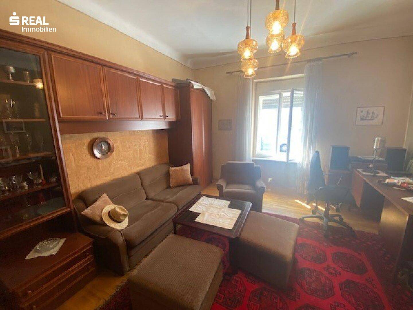 Gemütlicher Wohnbereich mit Holzmöbeln, Sofa und Blick auf den Außenbereich.