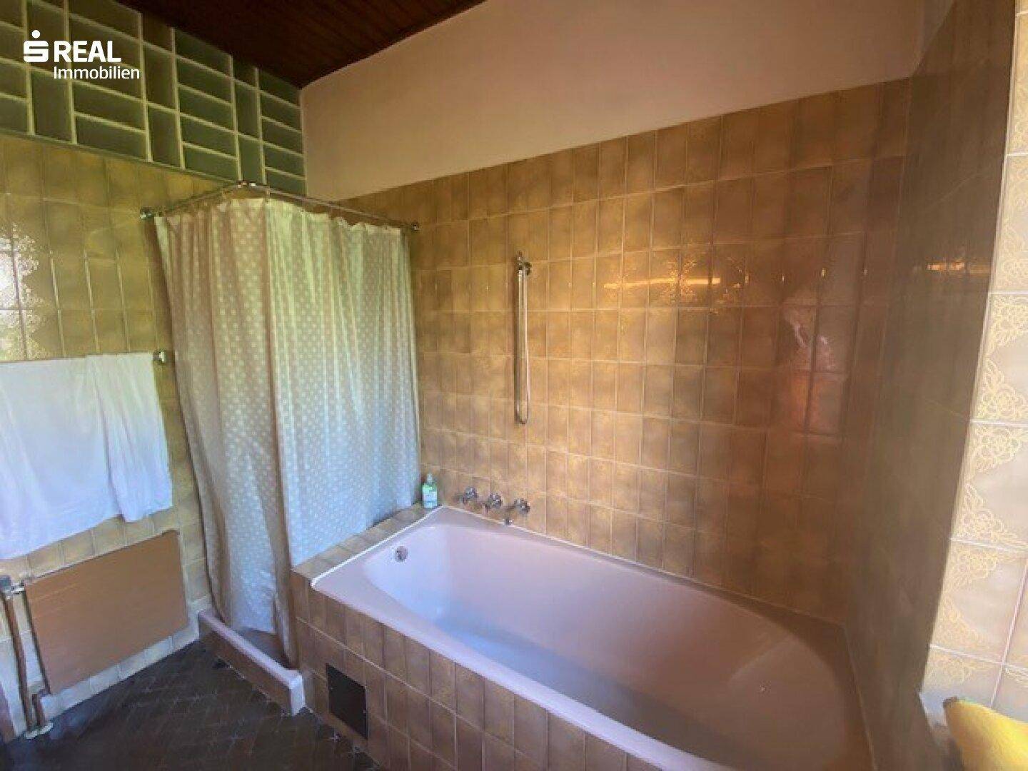 Badezimmer mit rosa Badewanne und braunen Fliesen, im Stil der 80er Jahre.