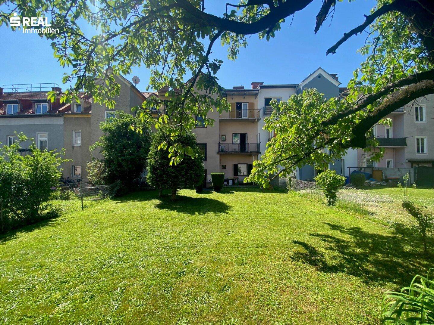 Weitläufiger Garten mit altem Baumbestand und Blick auf die Wohnhausfassade.