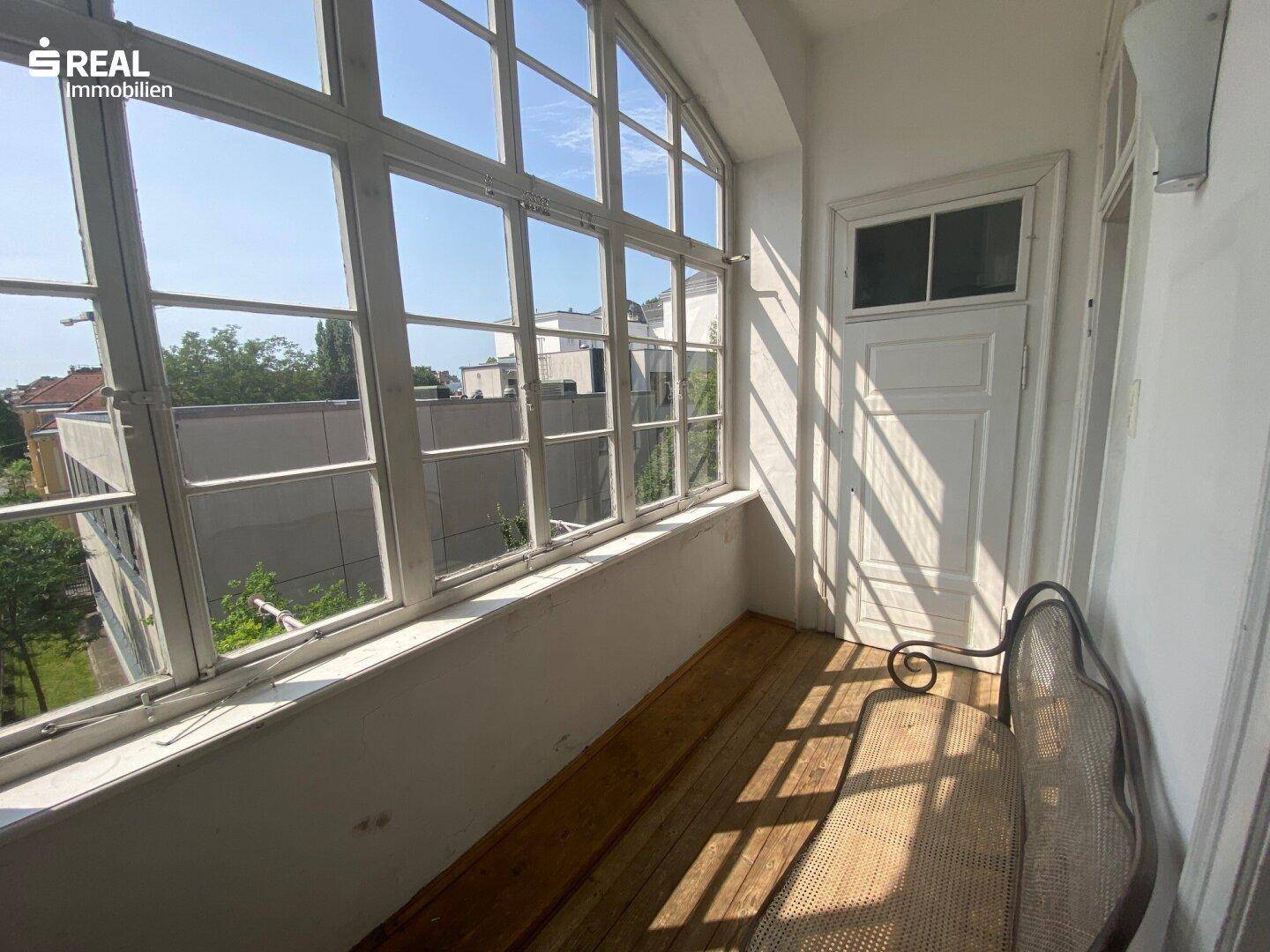 Heller, verglaster Balkon mit großen Fenstern und Holzboden, ideal zum Entspannen.
