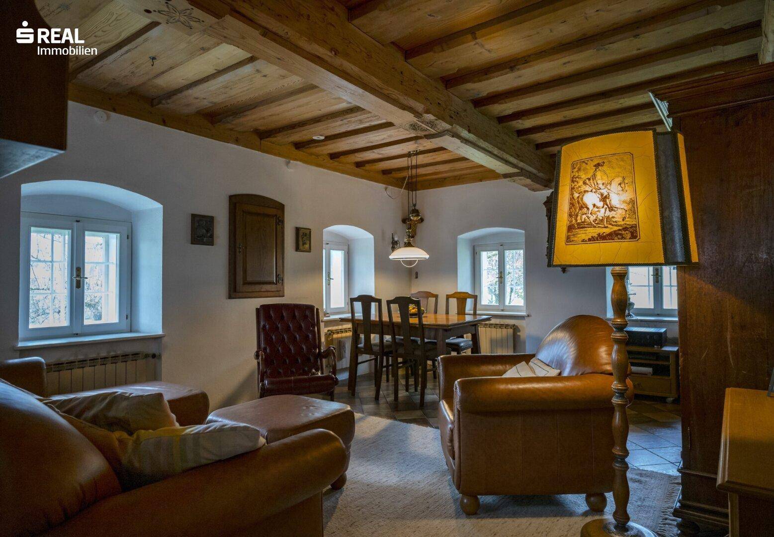 Gemütlicher Wohn- und Essbereich mit Holzbalkendecke, Ledermöbeln und traditionellem Flair.