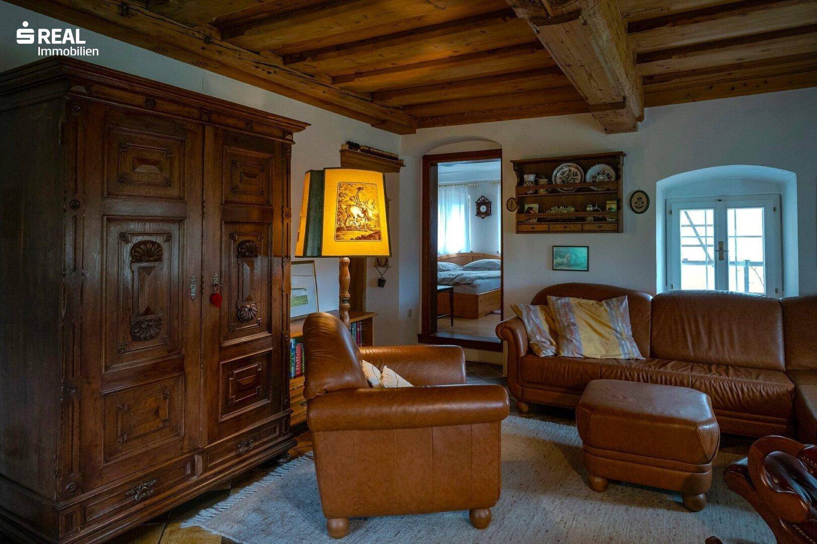 Rustikales Wohnzimmer mit Holzbalkendecke, antiken Möbeln und warmem Ambiente.