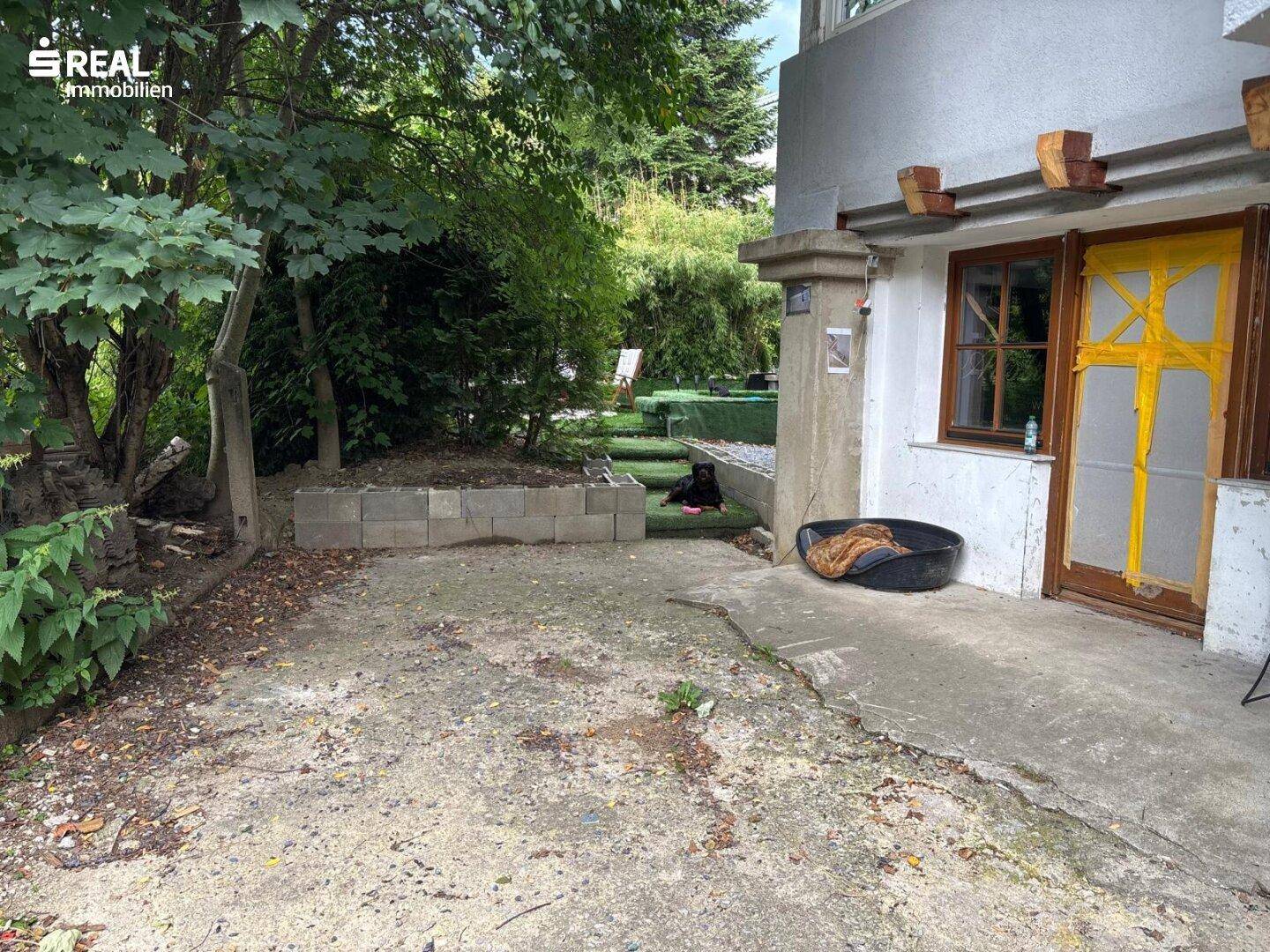 Gartenbereich mit Betonflächen und üppiger Vegetation, ideal für Entspannung im Freien.