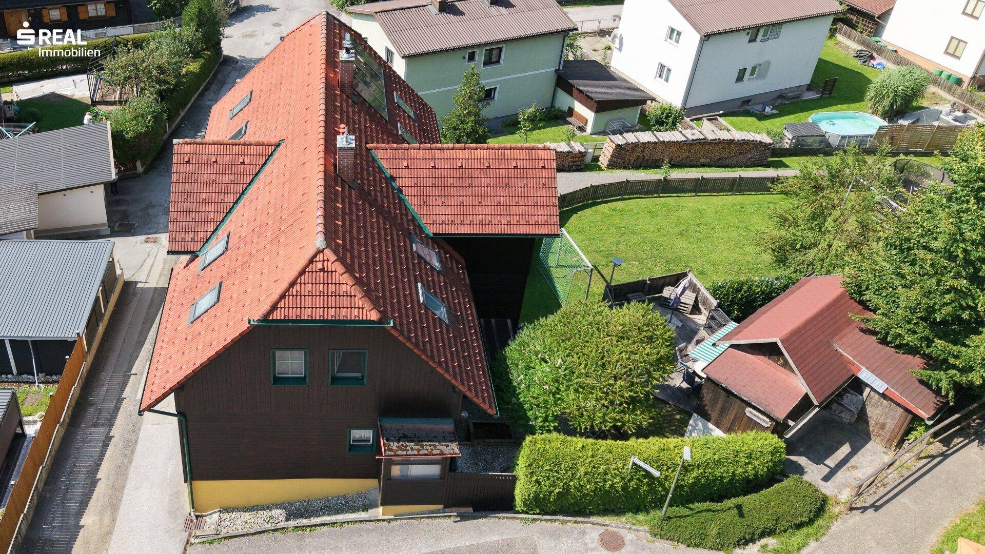 Luftaufnahme des Anwesens mit komplexer Dachlandschaft, umgeben von gepflegten Hecken und Grünflächen.