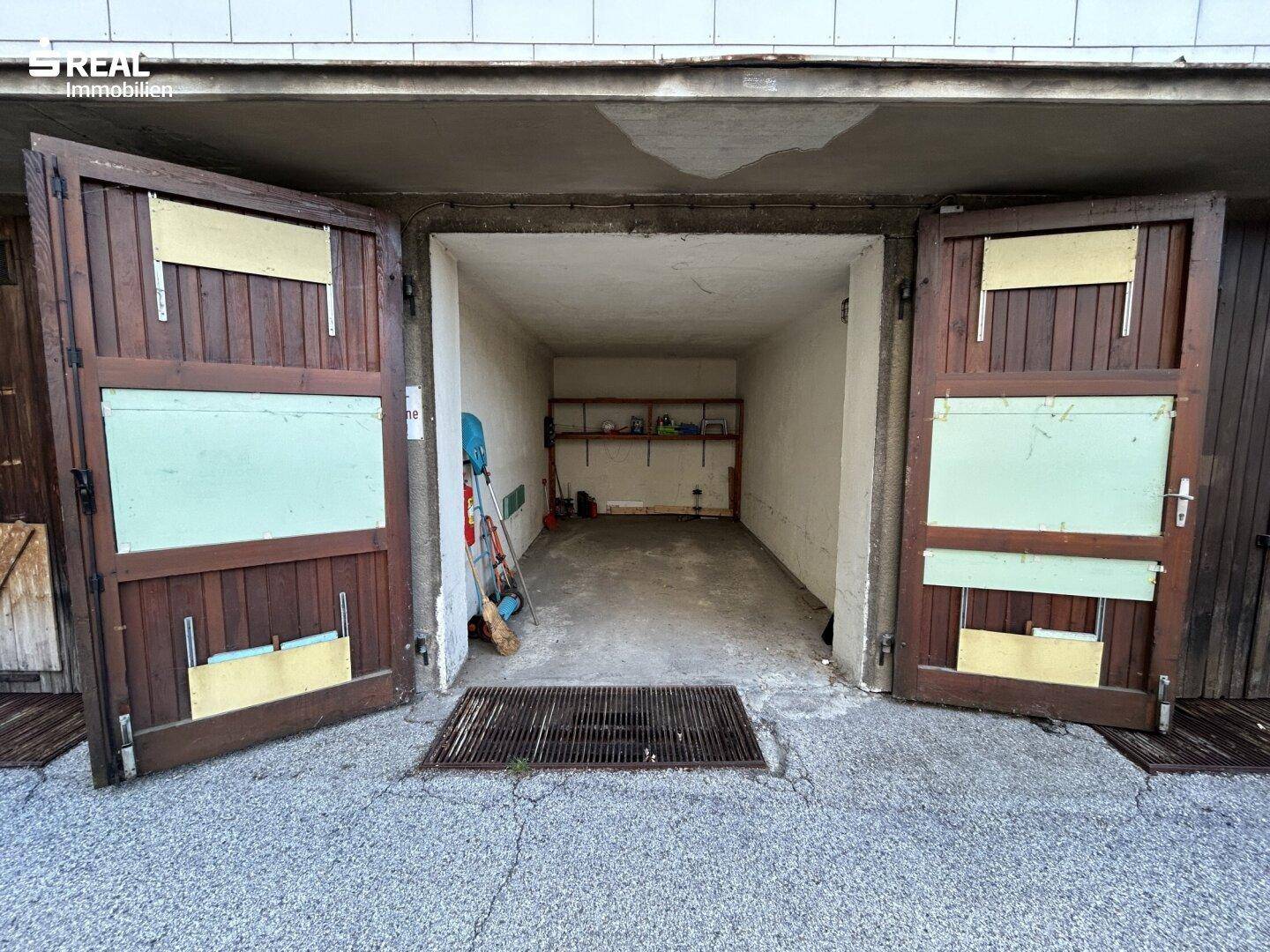 Einzelgarage mit rustikalen Holztoren und Stauraum im hinteren Bereich.