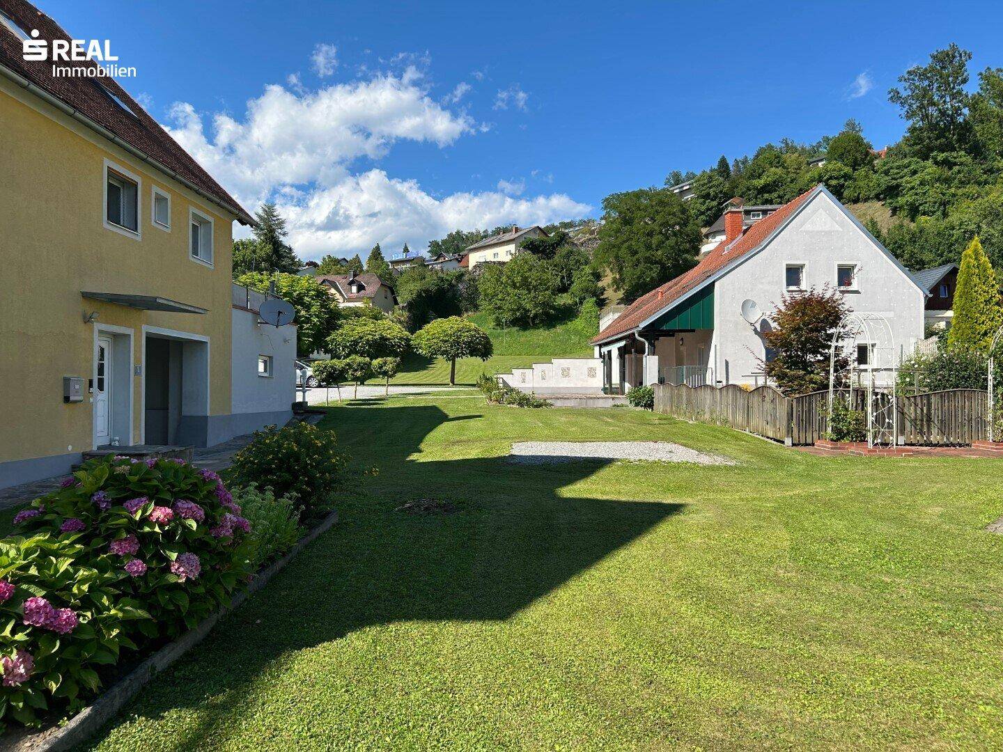 Gepflegter Gartenbereich mit blühenden Hortensien und Rasenfläche neben dem Wohngebäude.