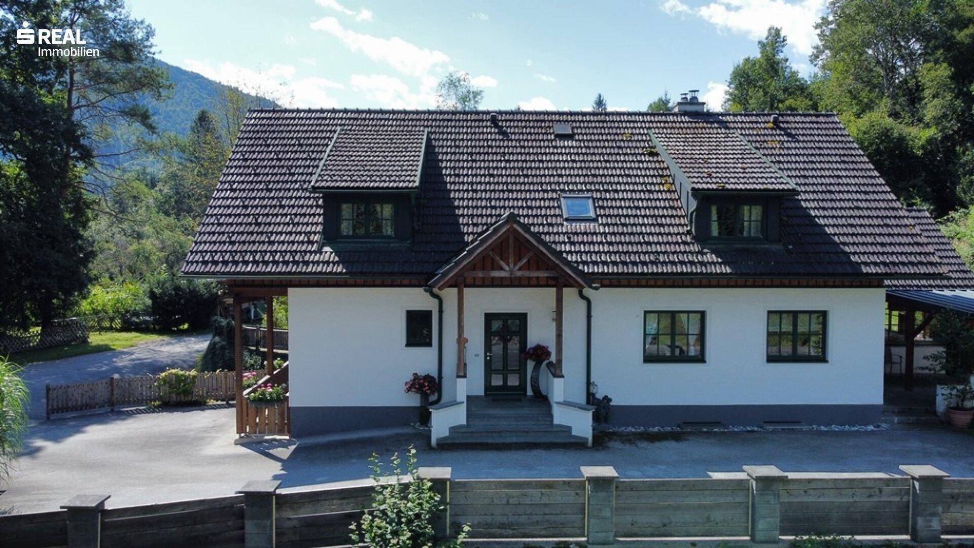 Einladendes Landhaus mit weißer Fassade, dunklem Dach und gepflegtem Eingangsbereich.