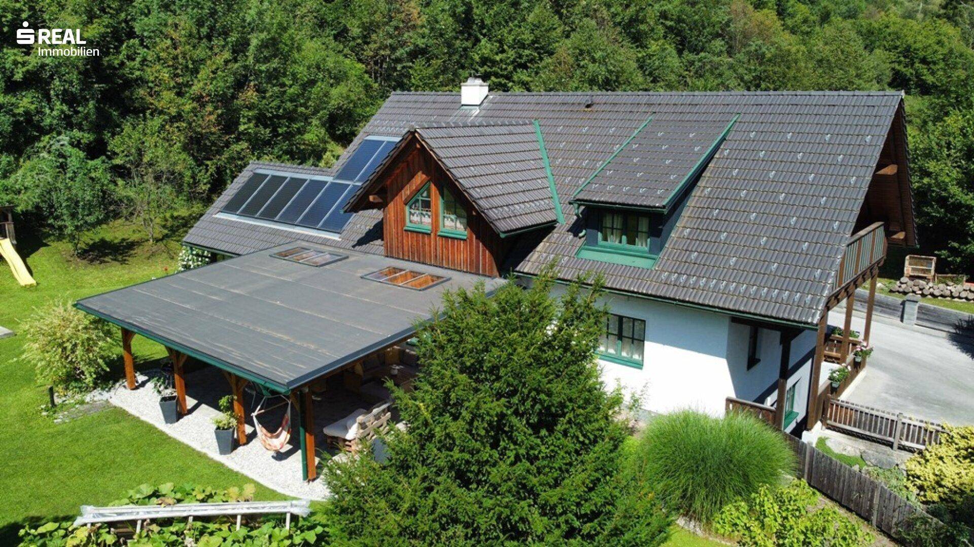 Vogelperspektive des Hauses mit Photovoltaikanlage, großem Garten und überdachtem Freisitz.